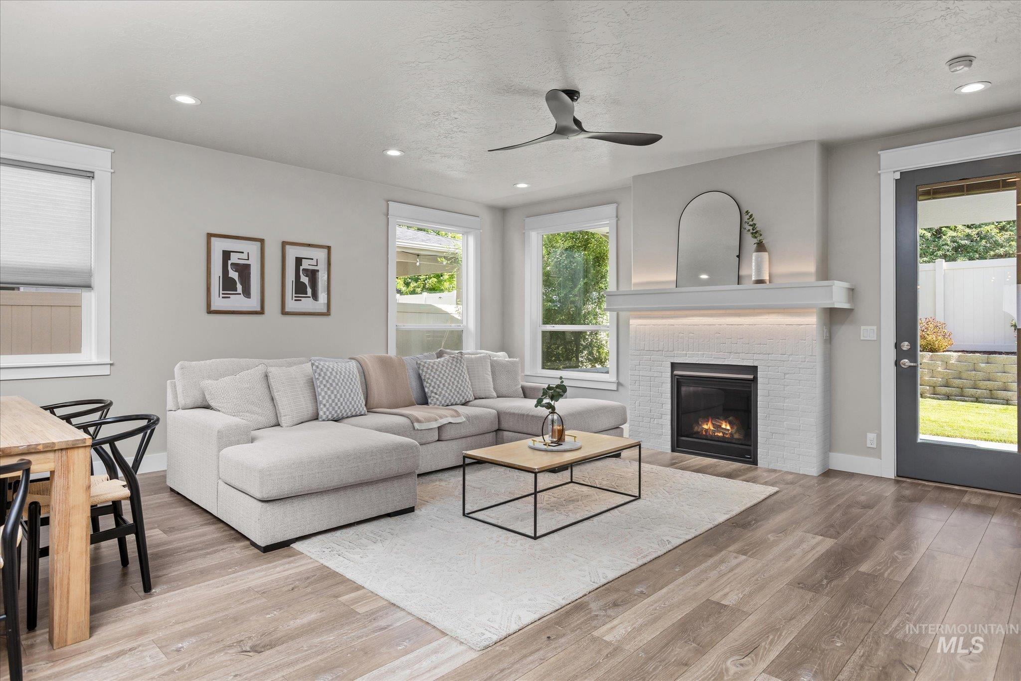 Living room featuring plenty of natural light, a fireplace, light wood-type flooring, a ceiling fan, and recessed lighting