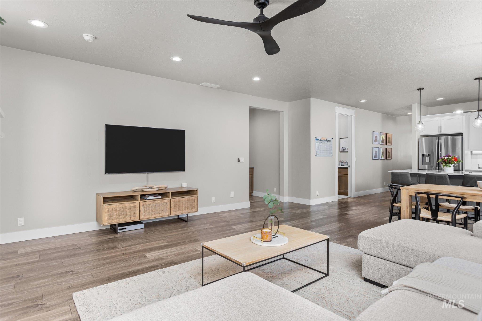 Living room with recessed lighting, a ceiling fan, wood finished floors, and a textured ceiling