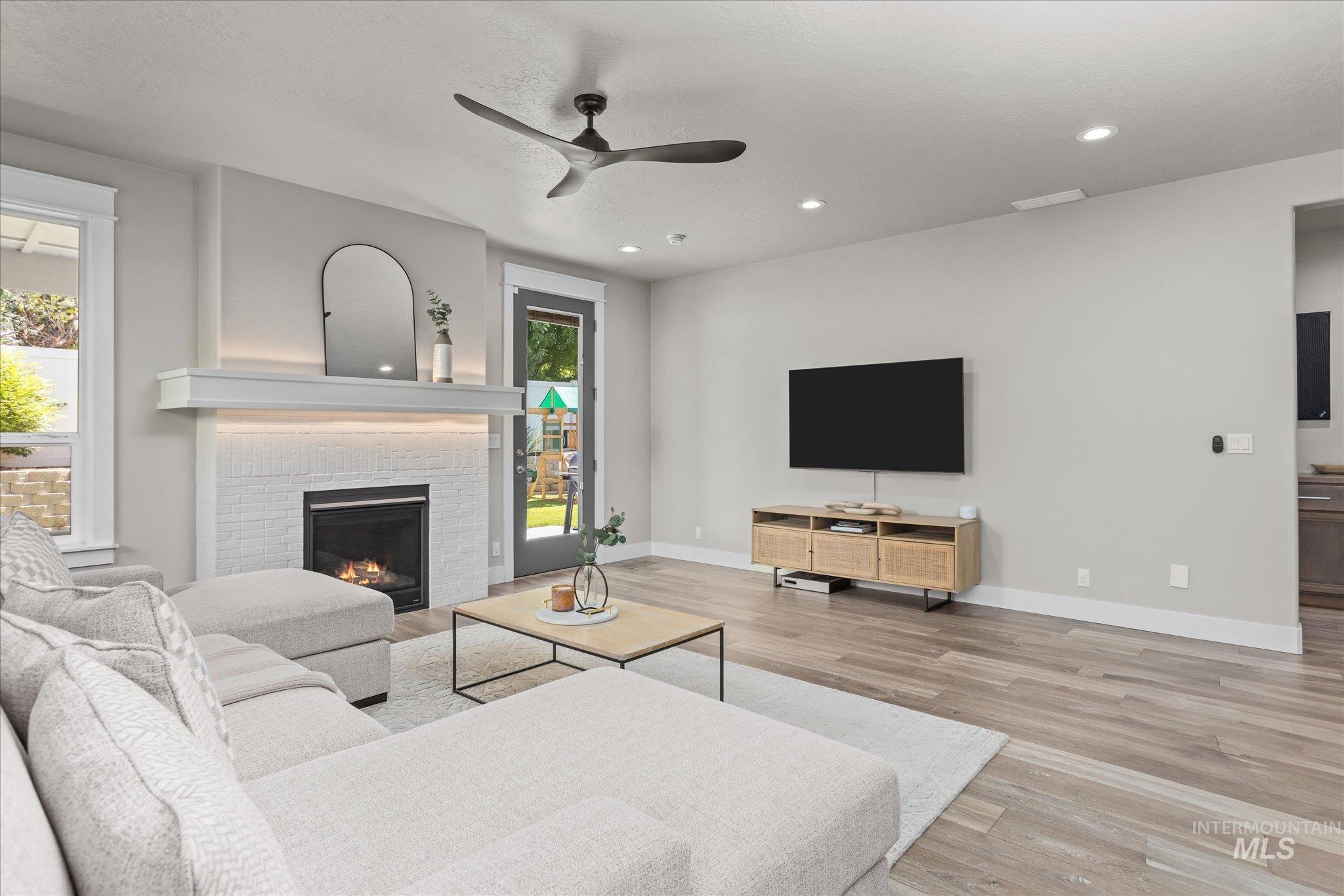 Living room with ceiling fan, wood finished floors, recessed lighting, and a brick fireplace