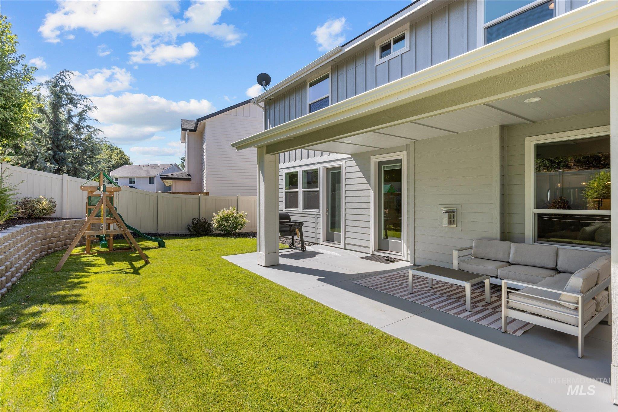Fenced backyard featuring a playground, a patio, and an outdoor hangout area