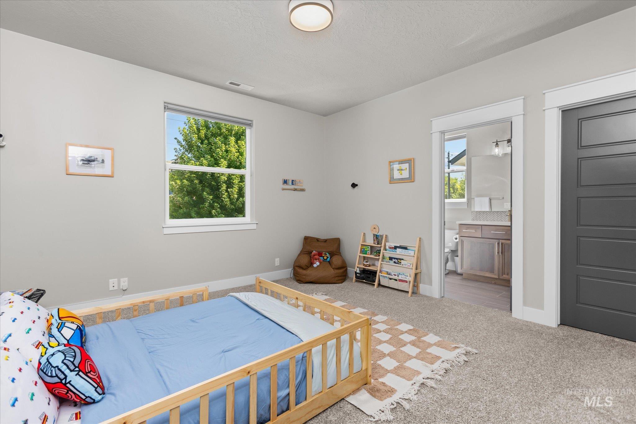 Carpeted bedroom featuring a textured ceiling and ensuite bath