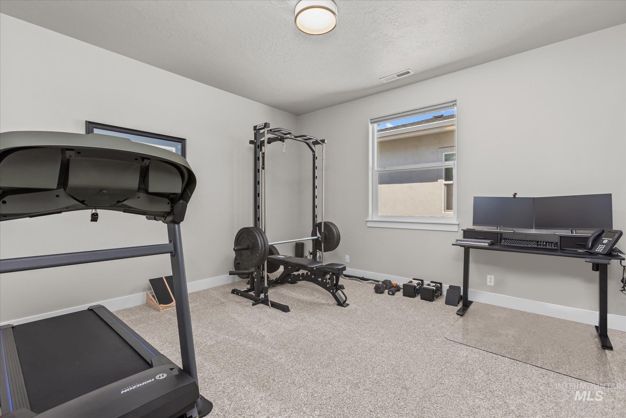 Workout room with carpet floors and a textured ceiling