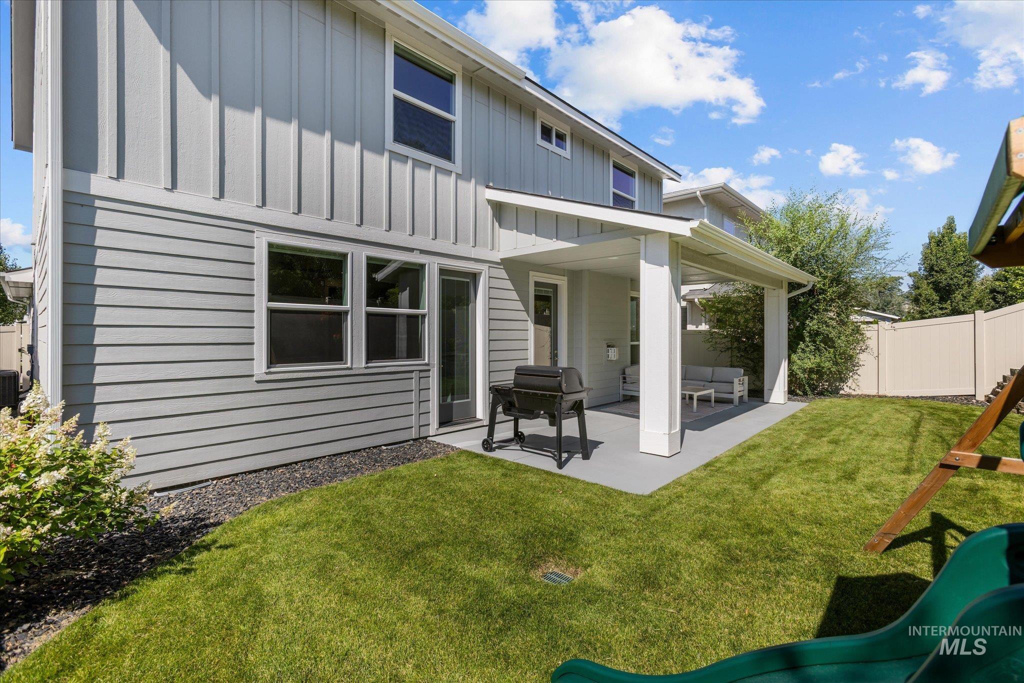 Rear view of house with board and batten siding, a patio area, and a playground