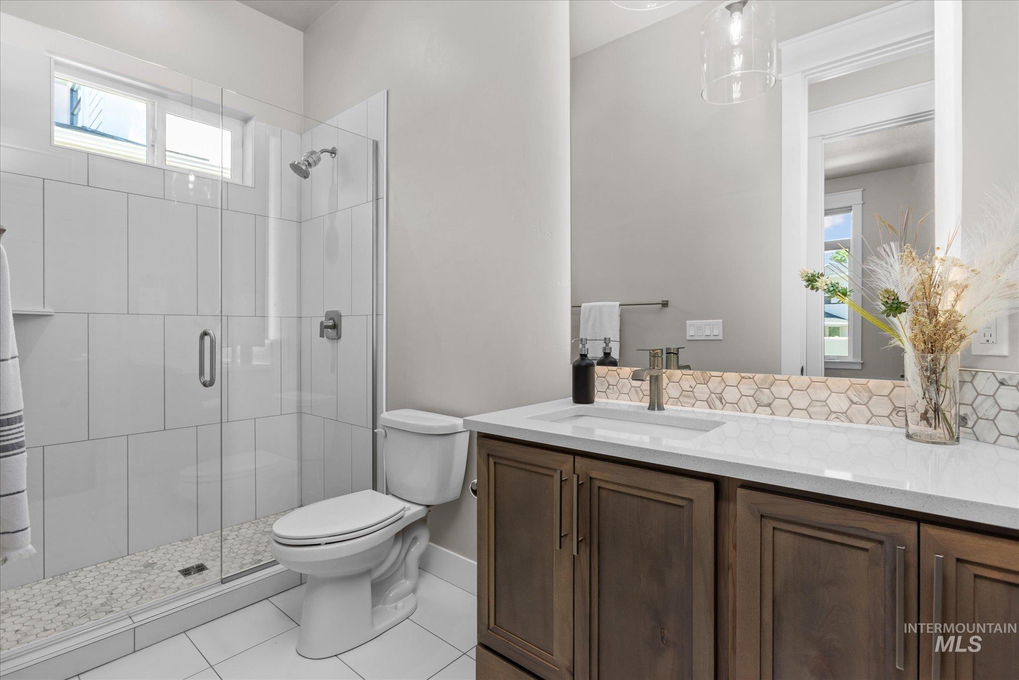 Bathroom with plenty of natural light, a shower stall, vanity, and tile patterned flooring