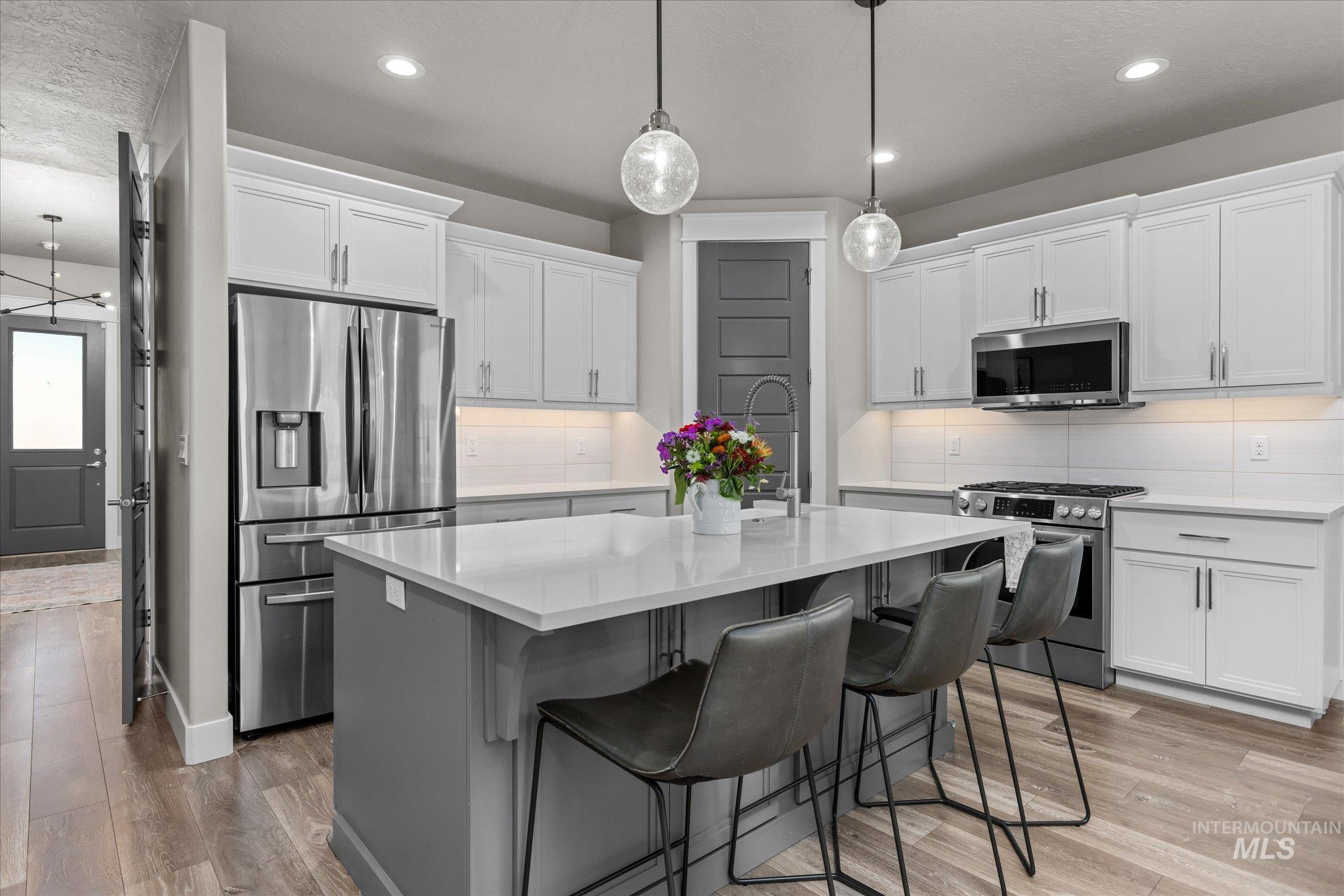 Kitchen featuring stainless steel appliances, decorative backsplash, light countertops, and recessed lighting