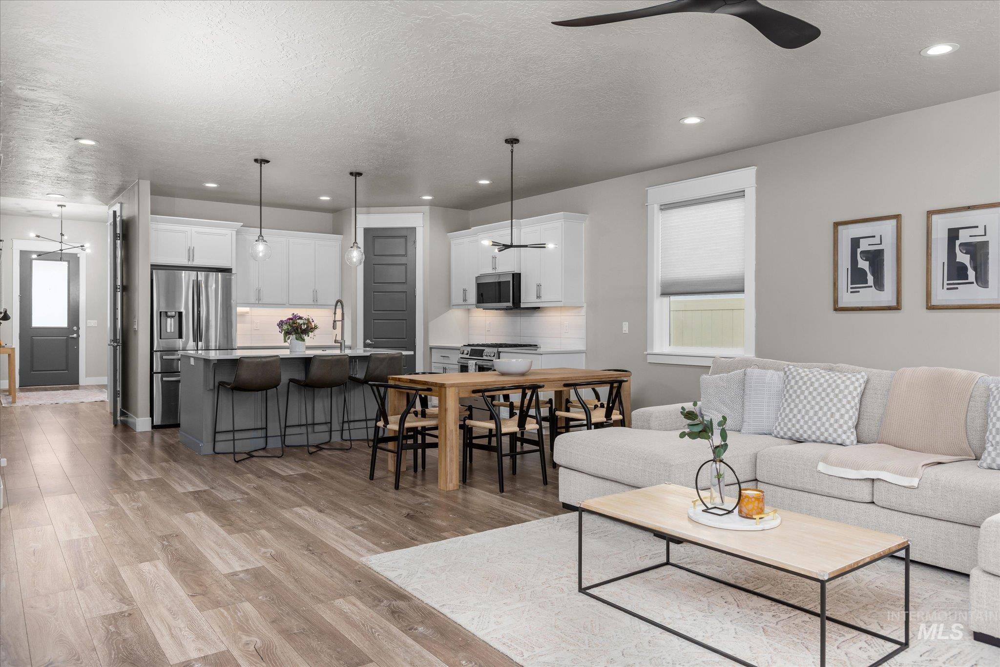 Living area featuring plenty of natural light, a textured ceiling, recessed lighting, light wood-style flooring, and a ceiling fan