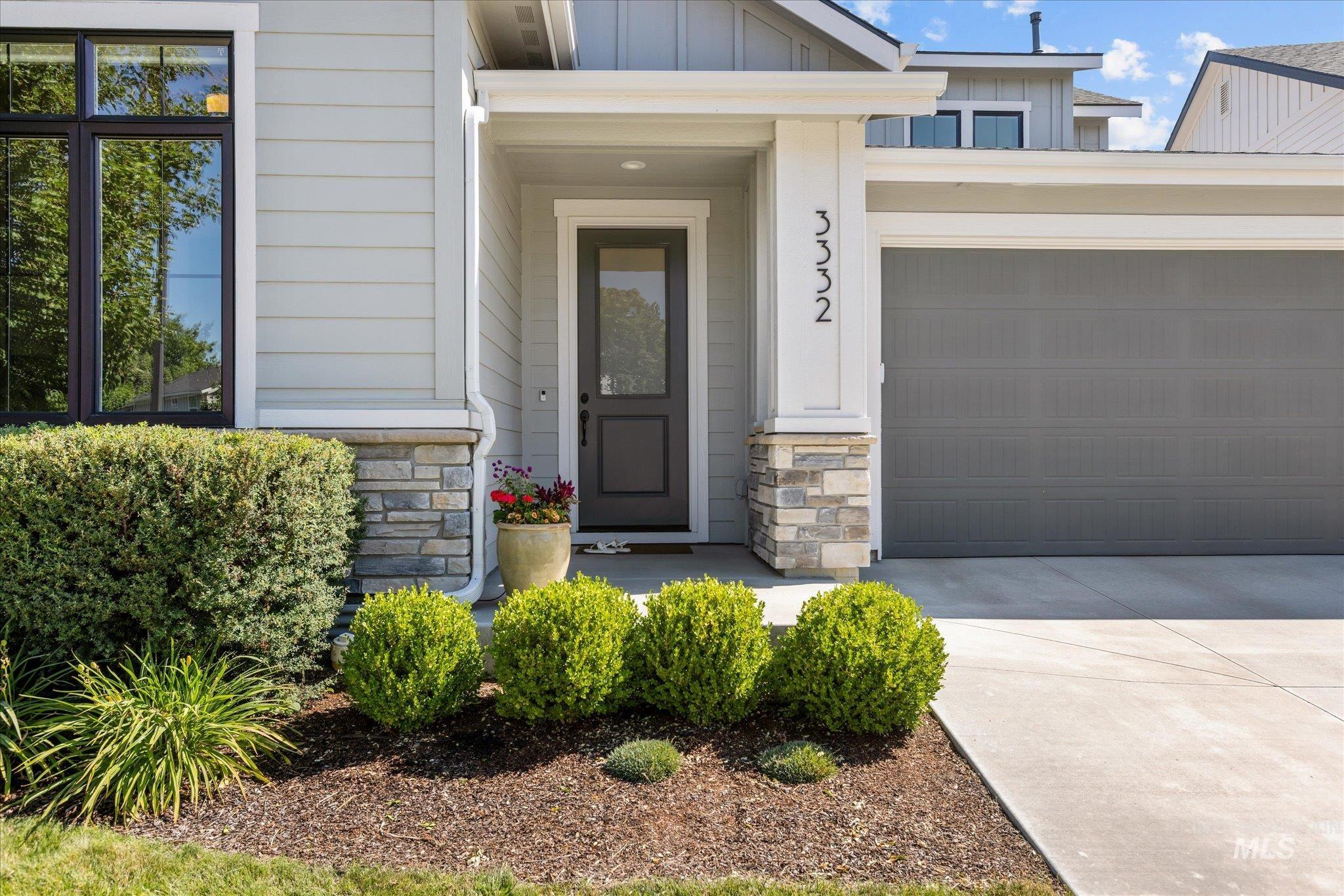 Entrance to property featuring board and batten siding, stone siding, driveway, and an attached garage