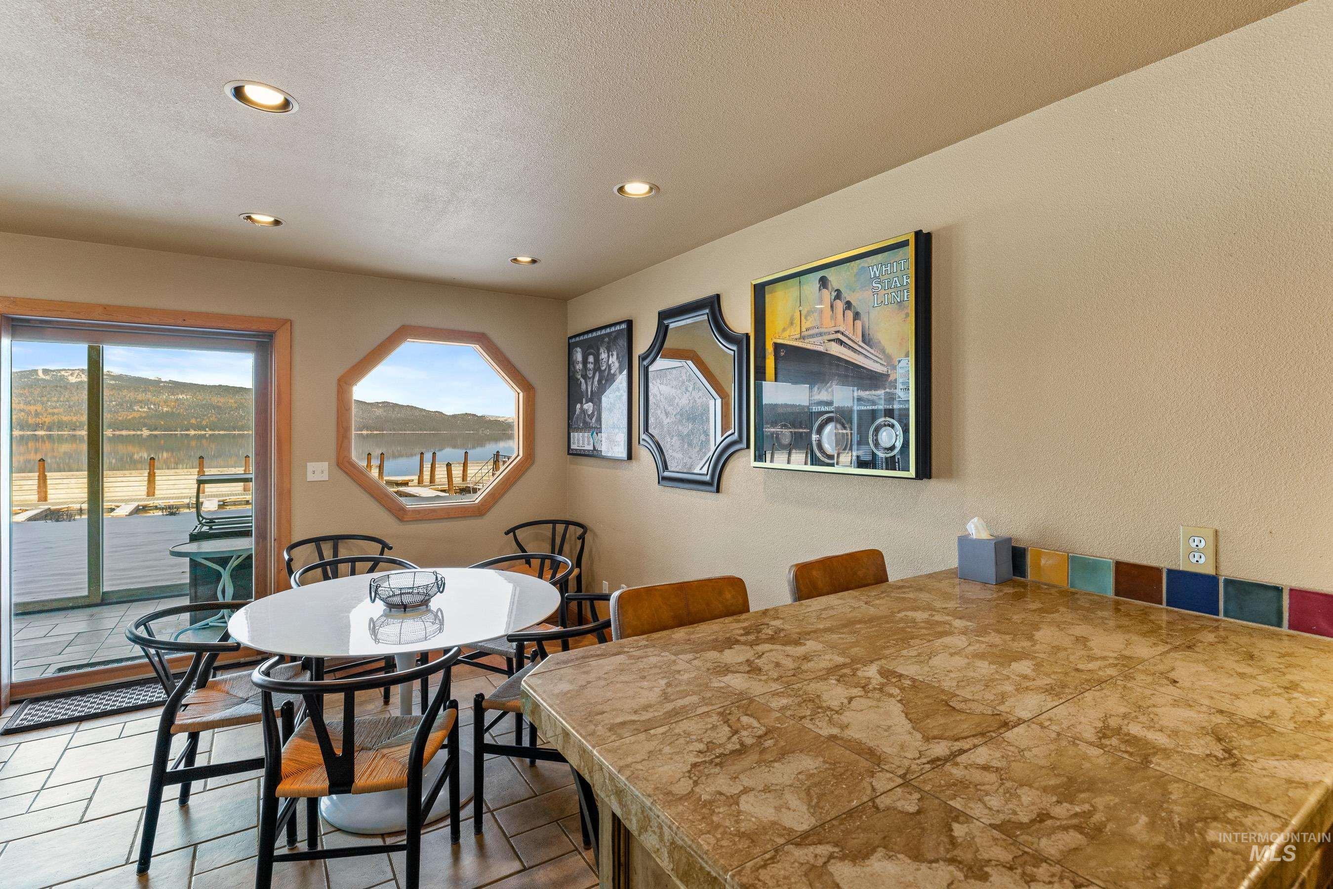 Dining space with recessed lighting, a textured wall, a textured ceiling, and a water view
