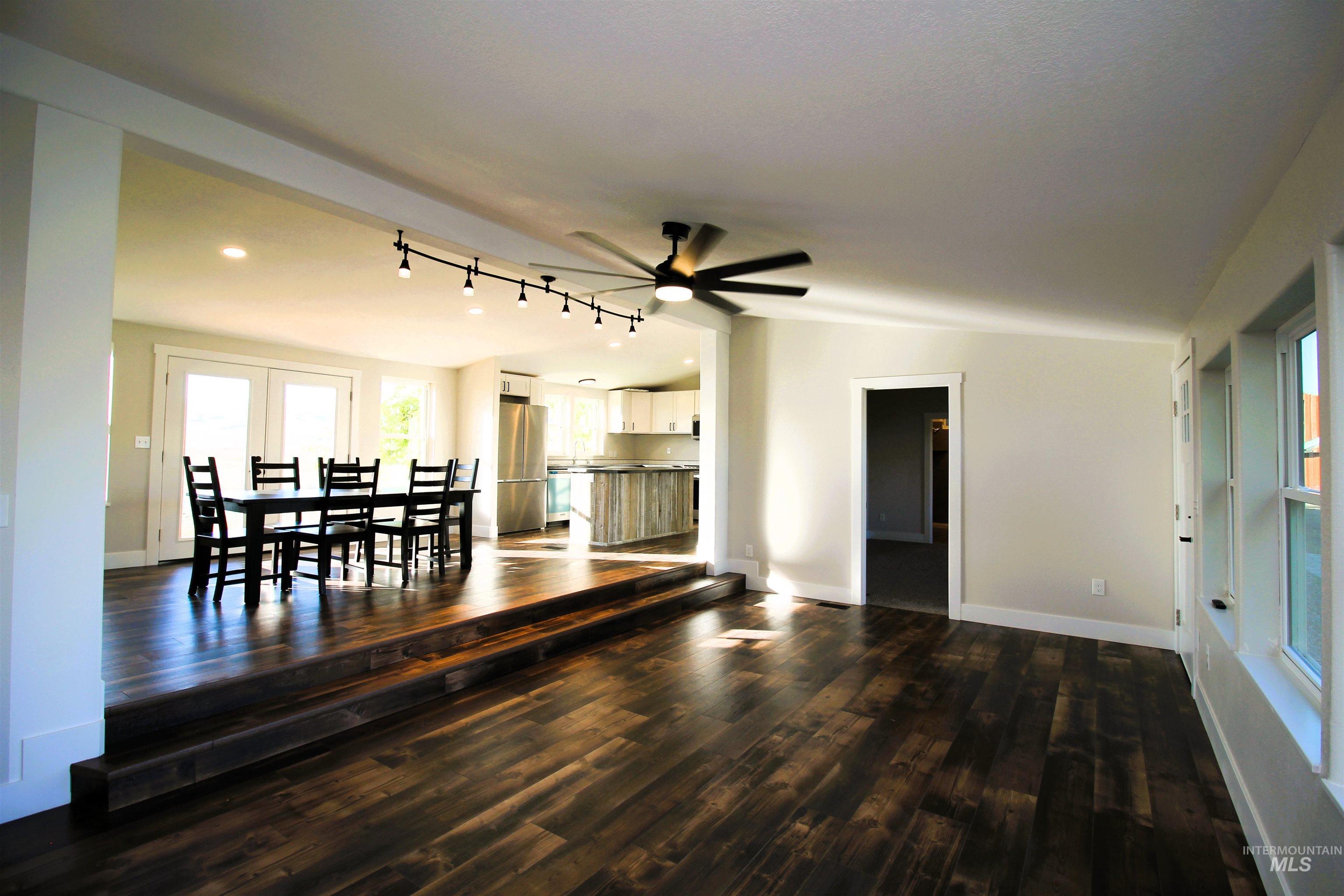 Dining room featuring lofted ceiling, dark wood finished floors, track lighting, and ceiling fan