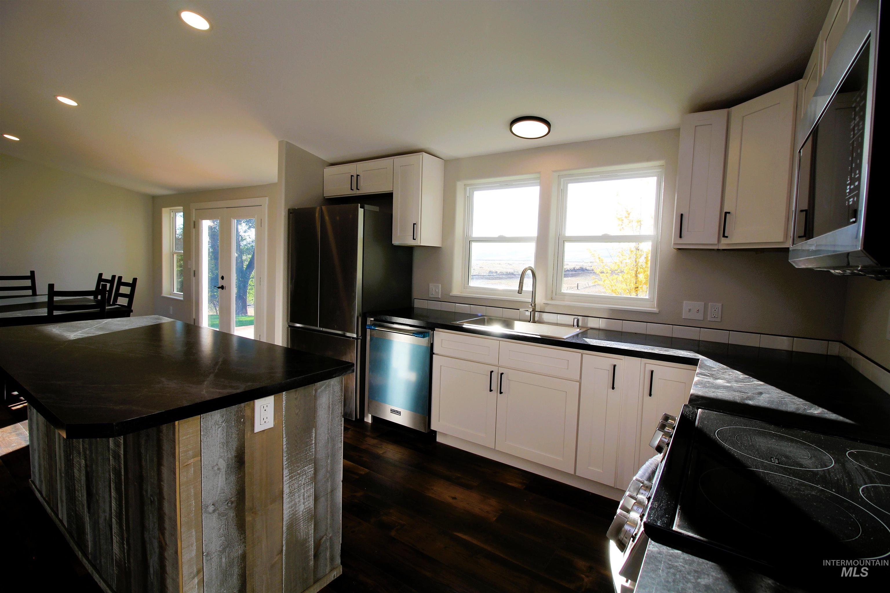 Kitchen featuring a kitchen island, recessed lighting, healthy amount of natural light, stainless steel appliances, and dark wood-type flooring
