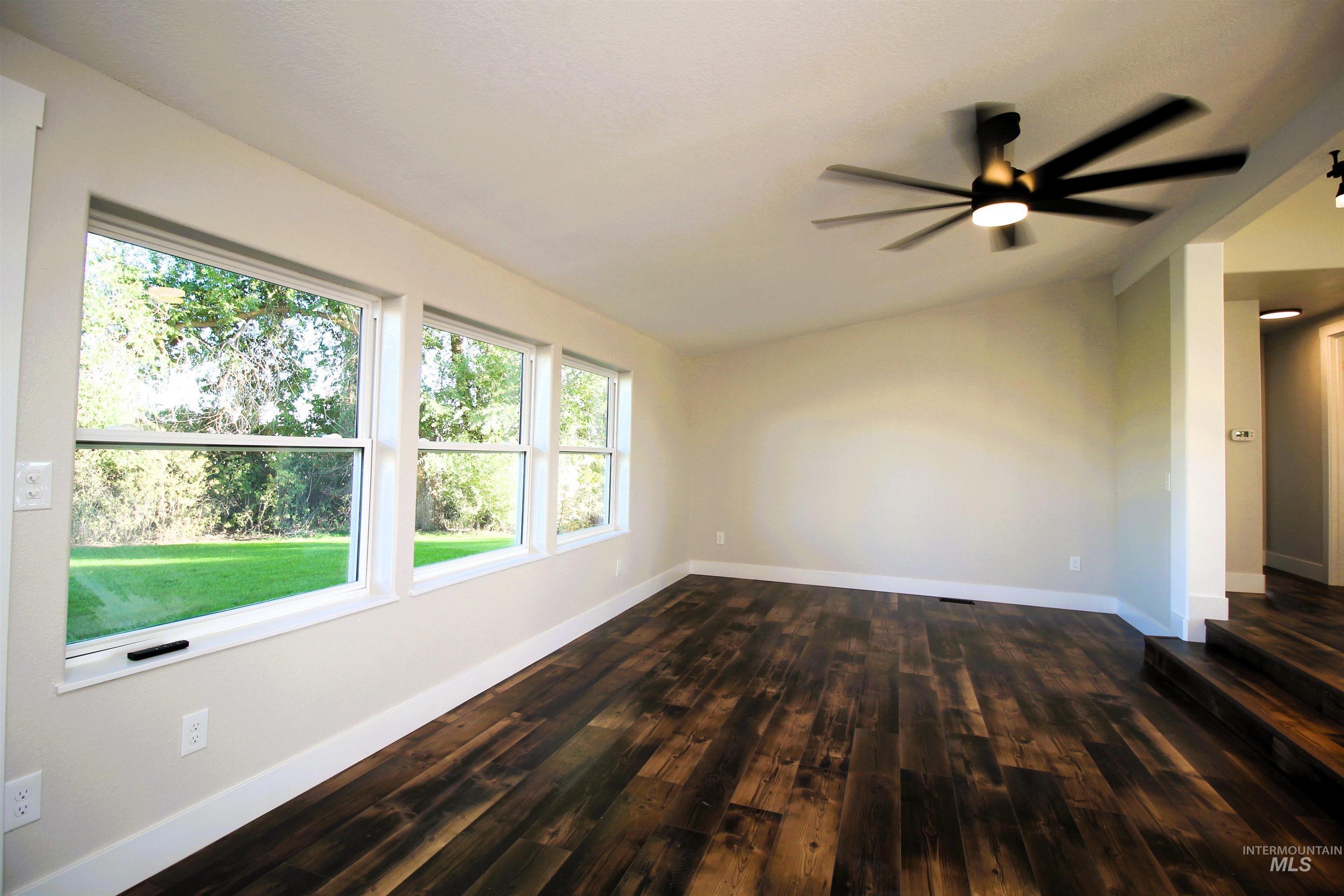 Spare room featuring lofted ceiling, dark wood-style flooring, and ceiling fan