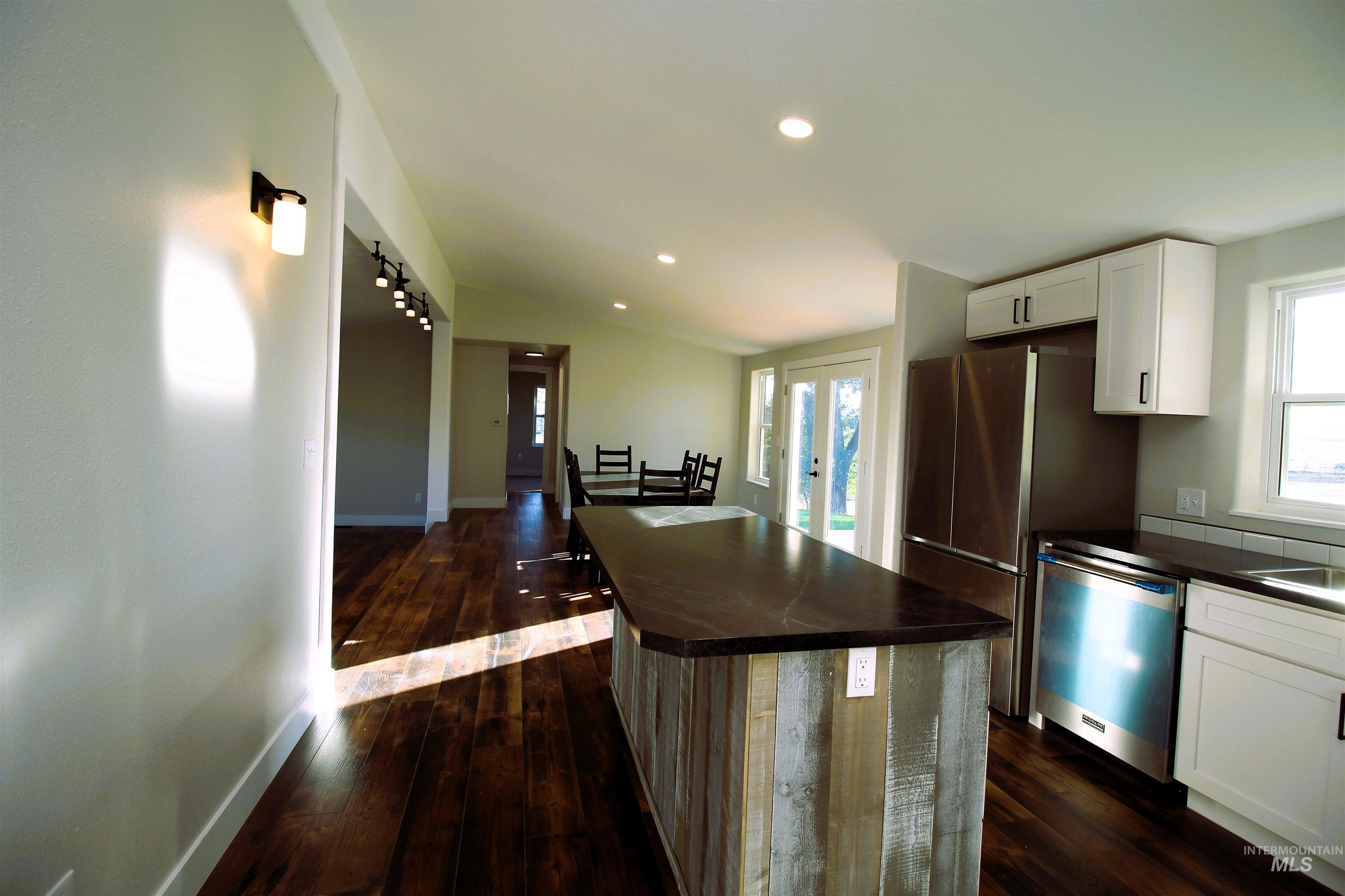 Kitchen with dark wood finished floors, recessed lighting, white cabinets, a kitchen island, and stainless steel dishwasher