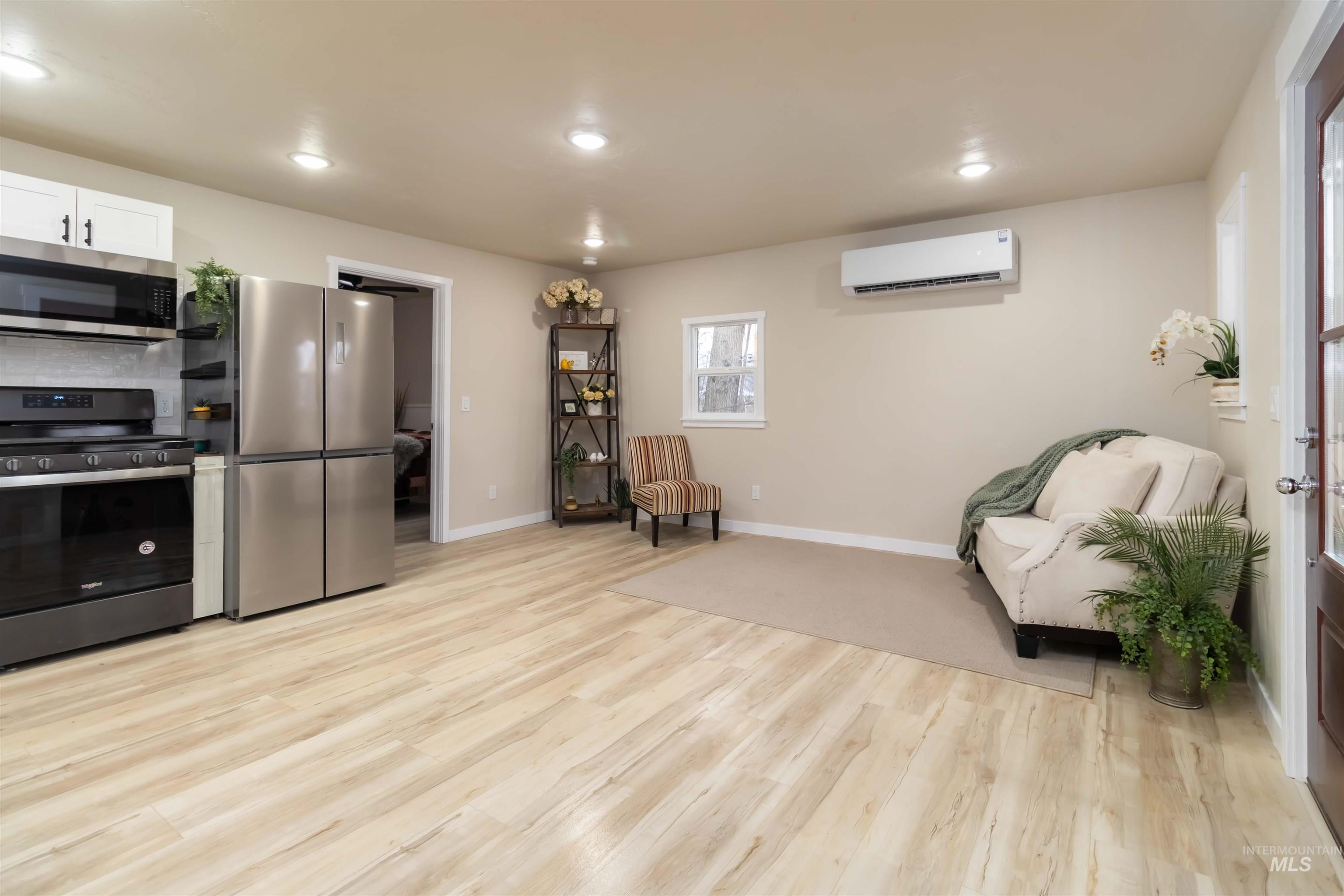 Living area with light wood finished floors and recessed lighting