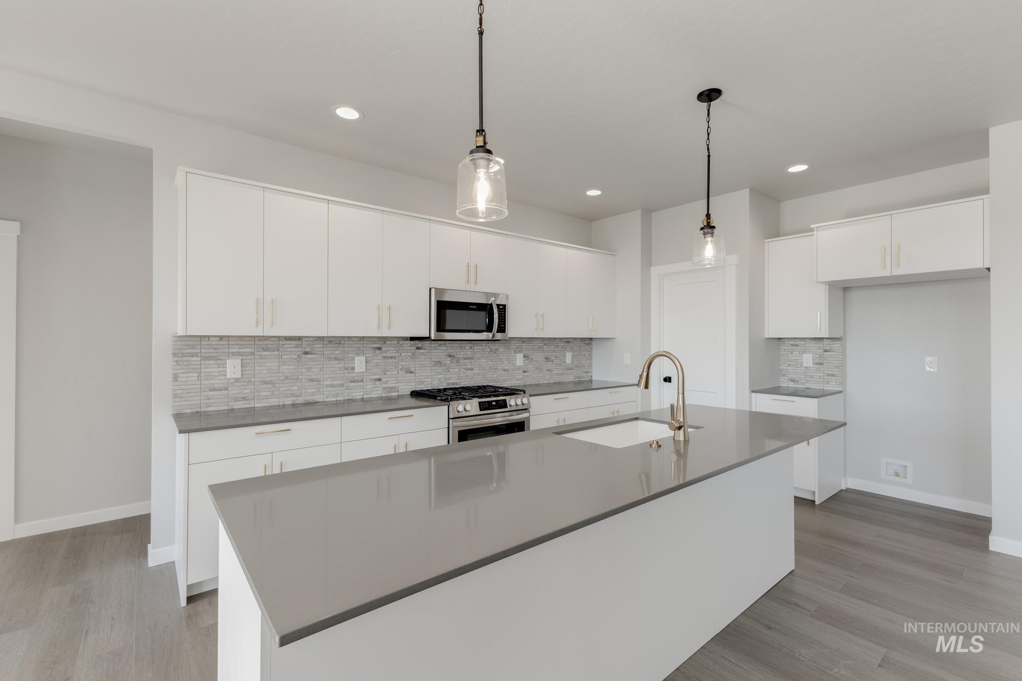 Kitchen featuring decorative backsplash, appliances with stainless steel finishes, white cabinetry, and recessed lighting