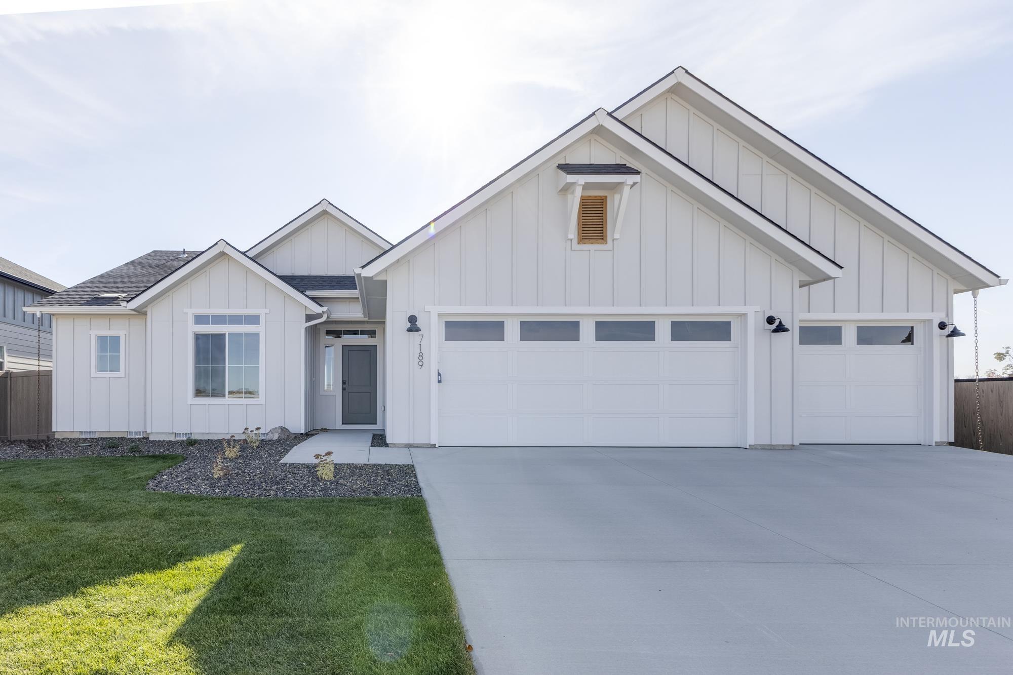 Modern farmhouse featuring board and batten siding, driveway, an attached garage, and a shingled roof