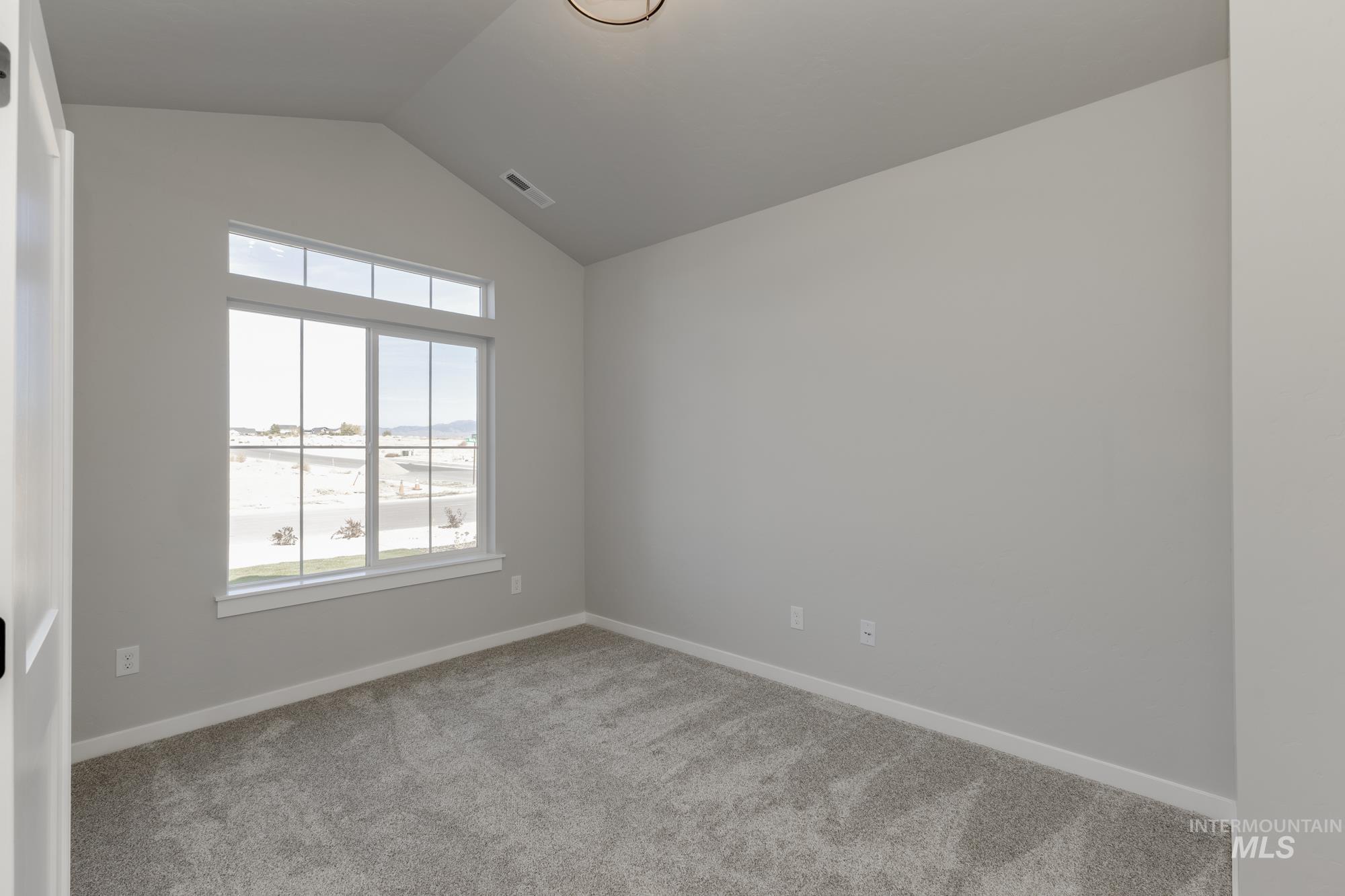 Spare room featuring vaulted ceiling and light carpet