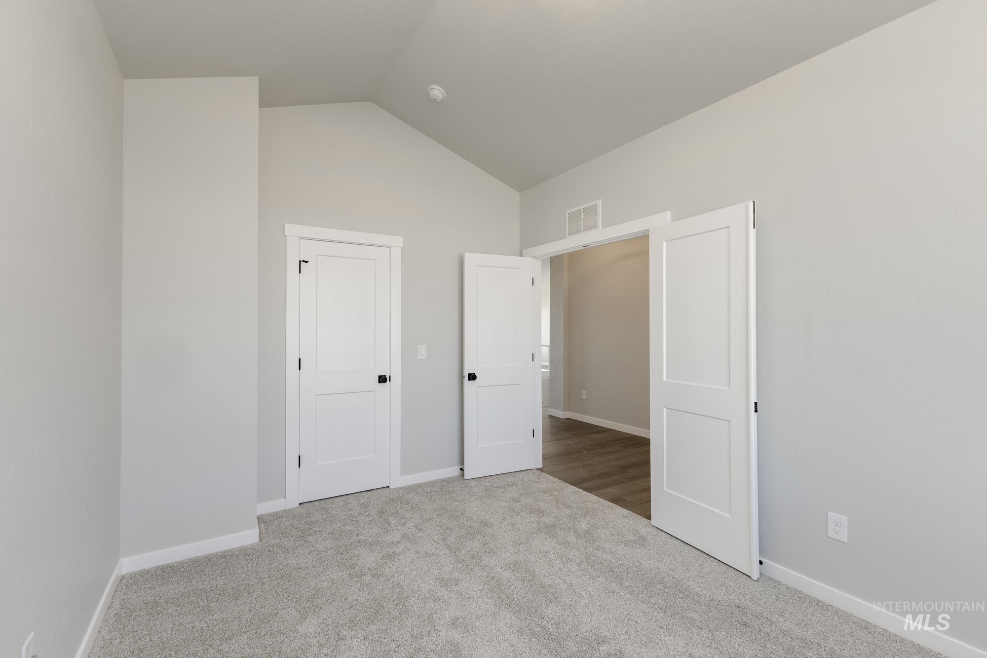 Unfurnished bedroom with lofted ceiling and carpet flooring