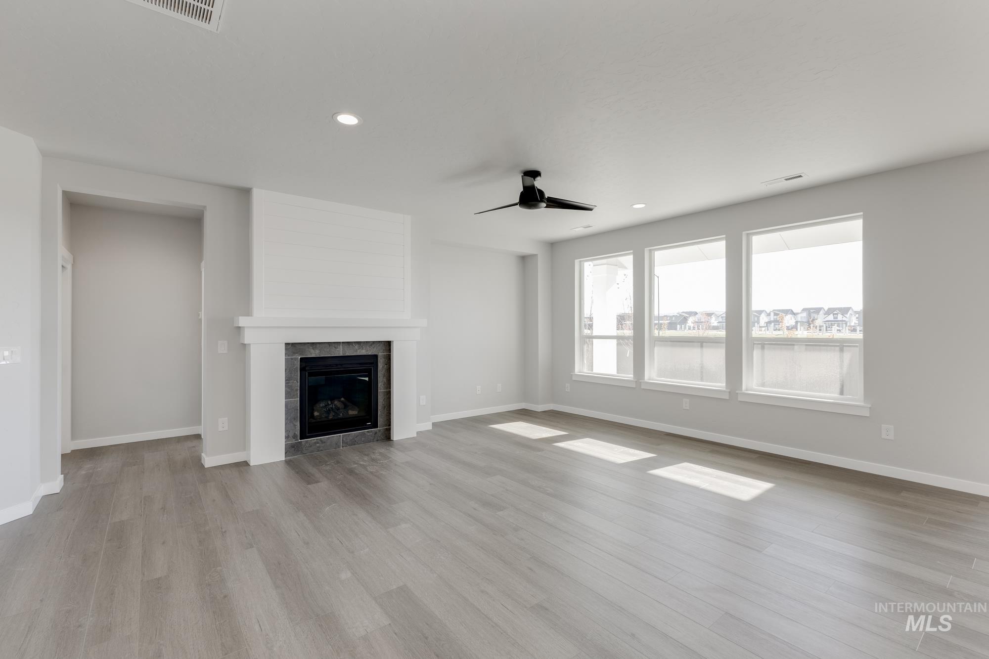Unfurnished living room with recessed lighting, light wood finished floors, ceiling fan, and a tiled fireplace