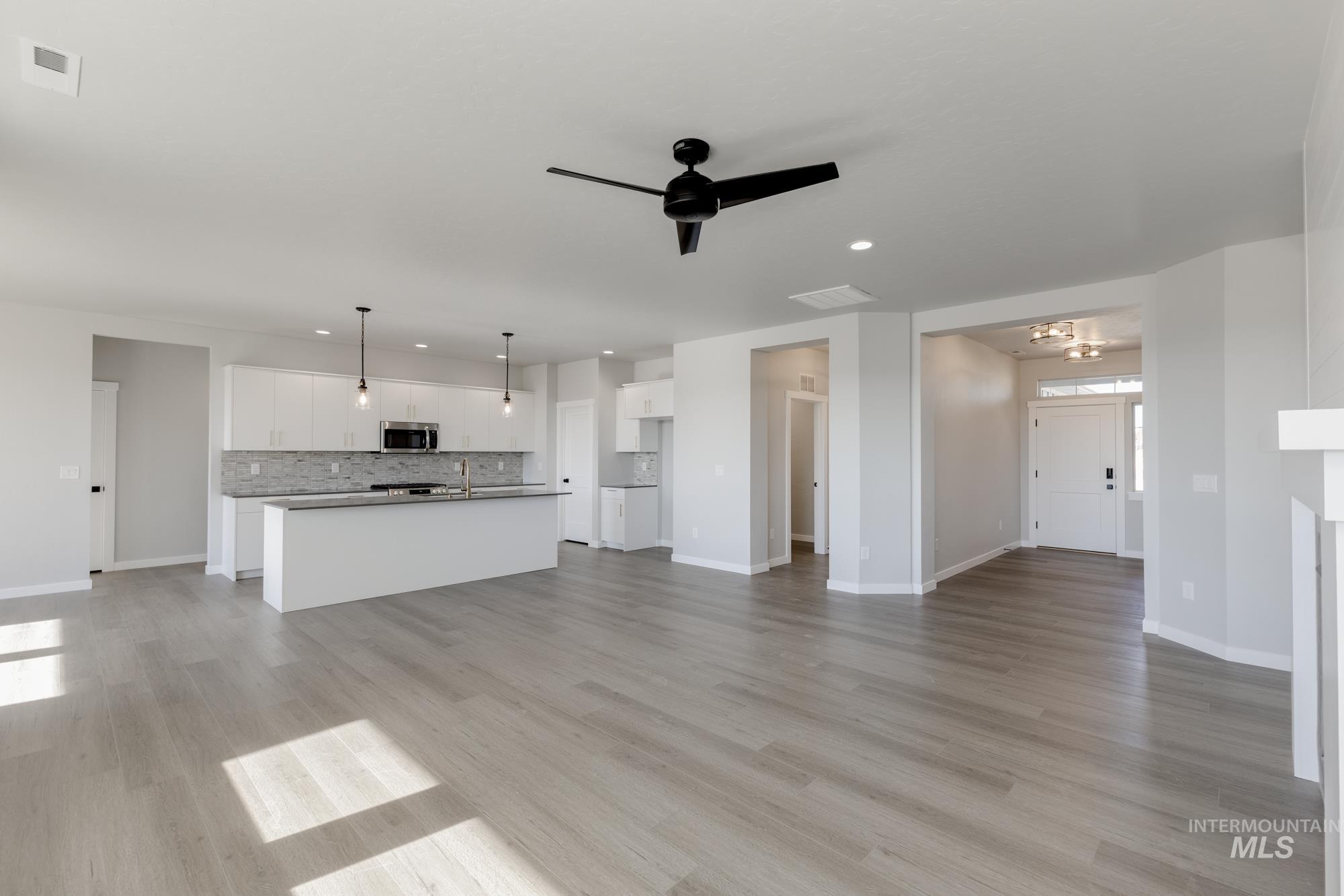 Unfurnished living room featuring recessed lighting, ceiling fan, light wood-type flooring, and a chandelier