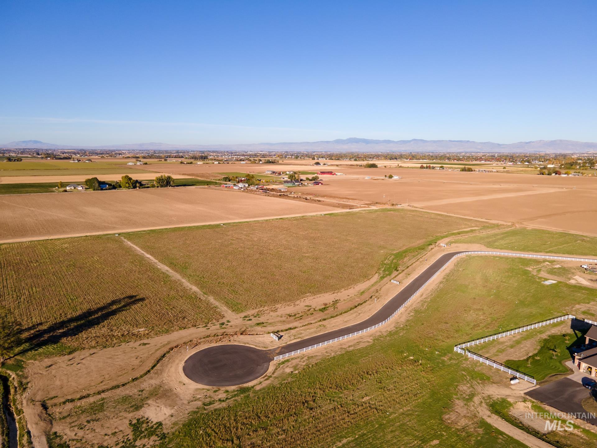 Aerial overview of property's location with rural landscape, mountains, and rows of crops