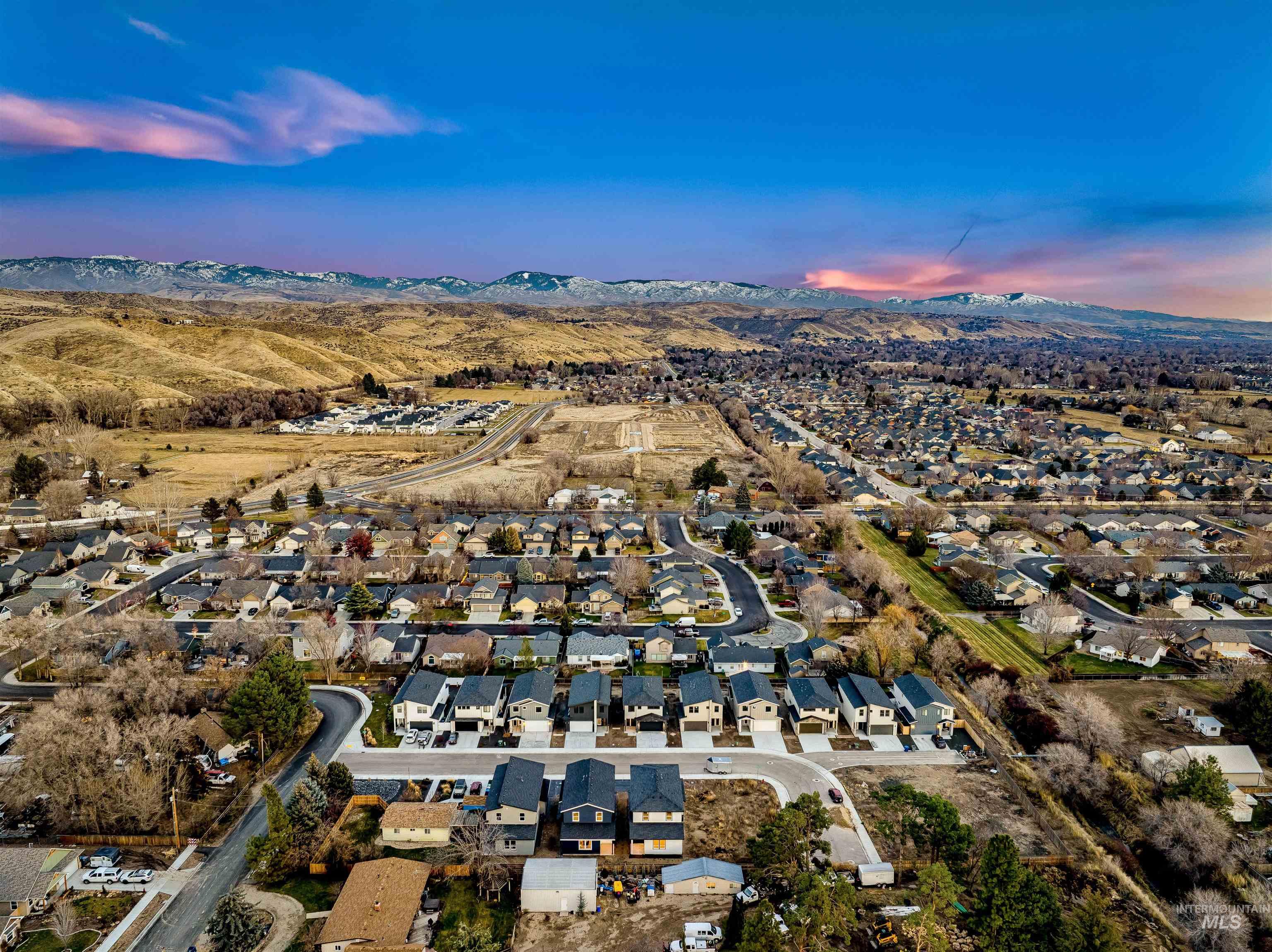 Aerial view of property and surrounding area with nearby suburban area and a mountainous background
