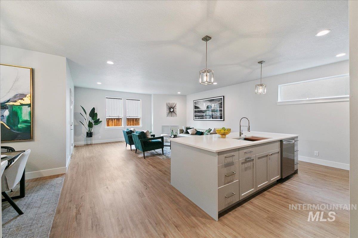 Kitchen featuring plenty of natural light, a center island with sink, light wood-type flooring, open floor plan, and recessed lighting
