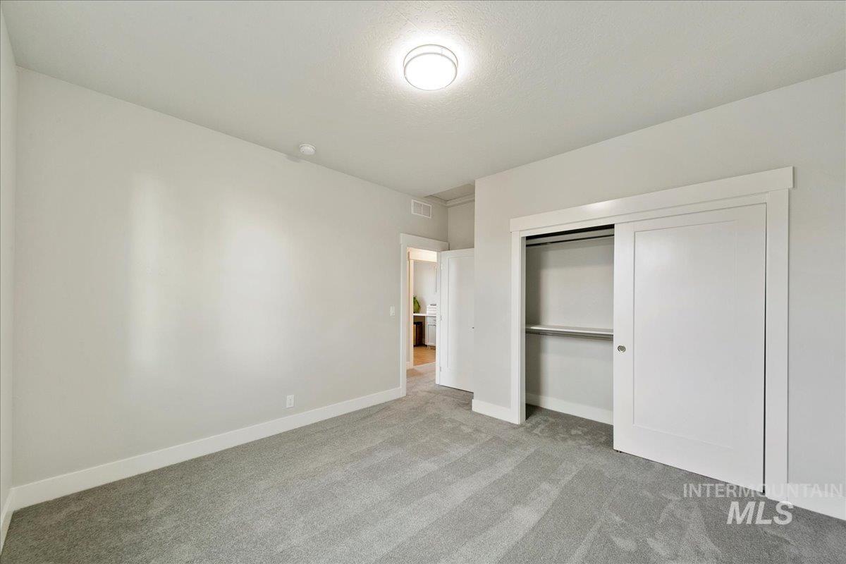Unfurnished bedroom with light colored carpet, a closet, and a textured ceiling