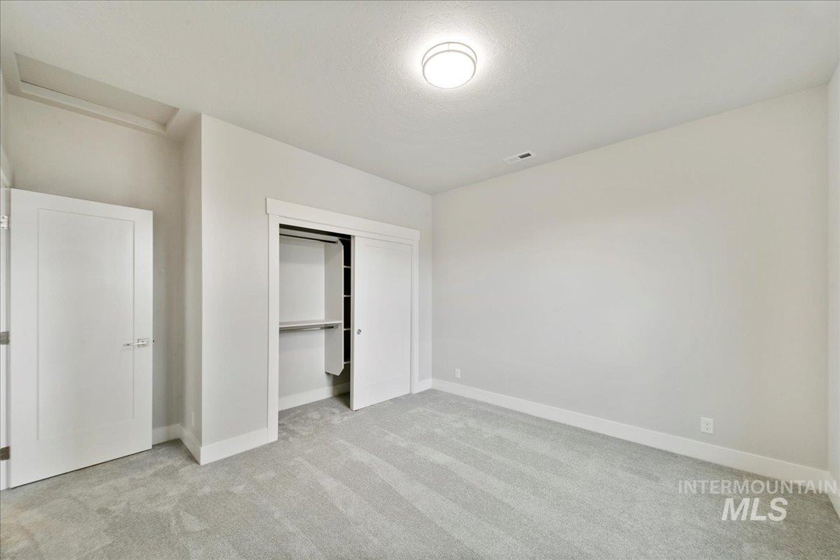 Unfurnished bedroom with light colored carpet, a closet, and a textured ceiling