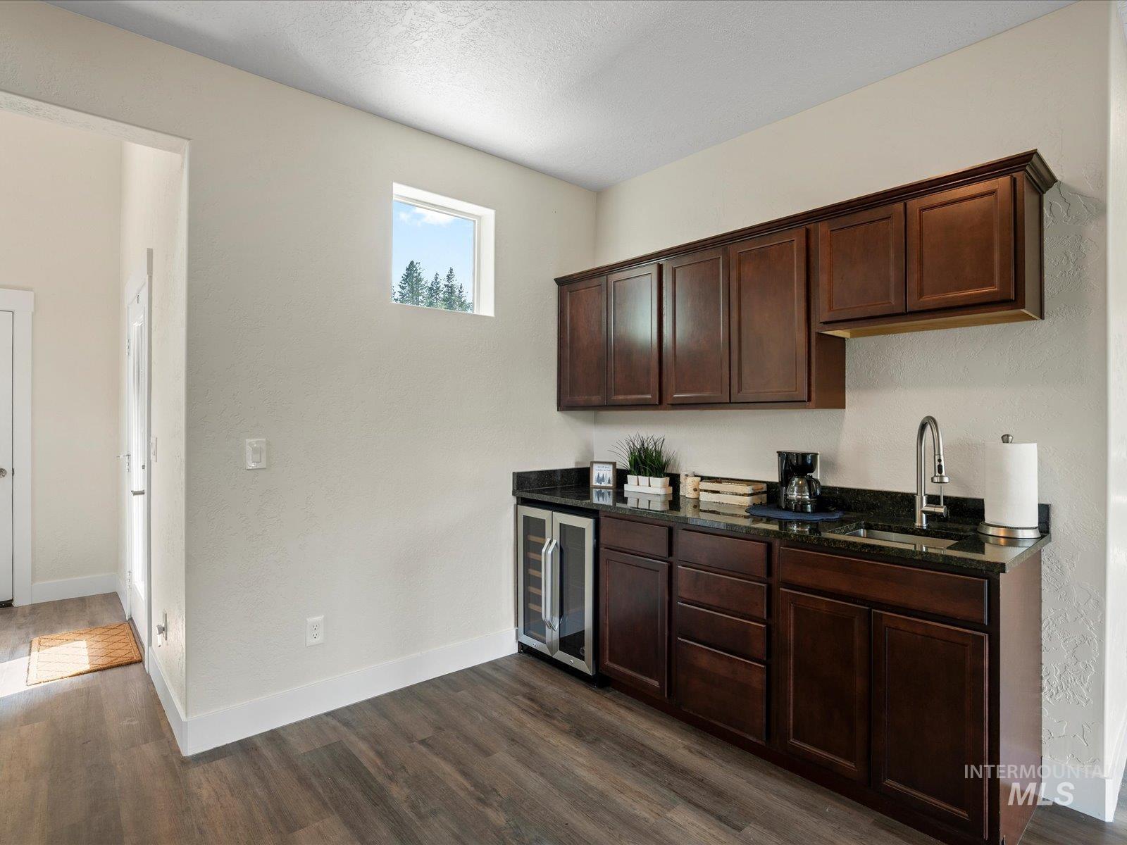 Bar area featuring beverage cooler and dark wood-style flooring