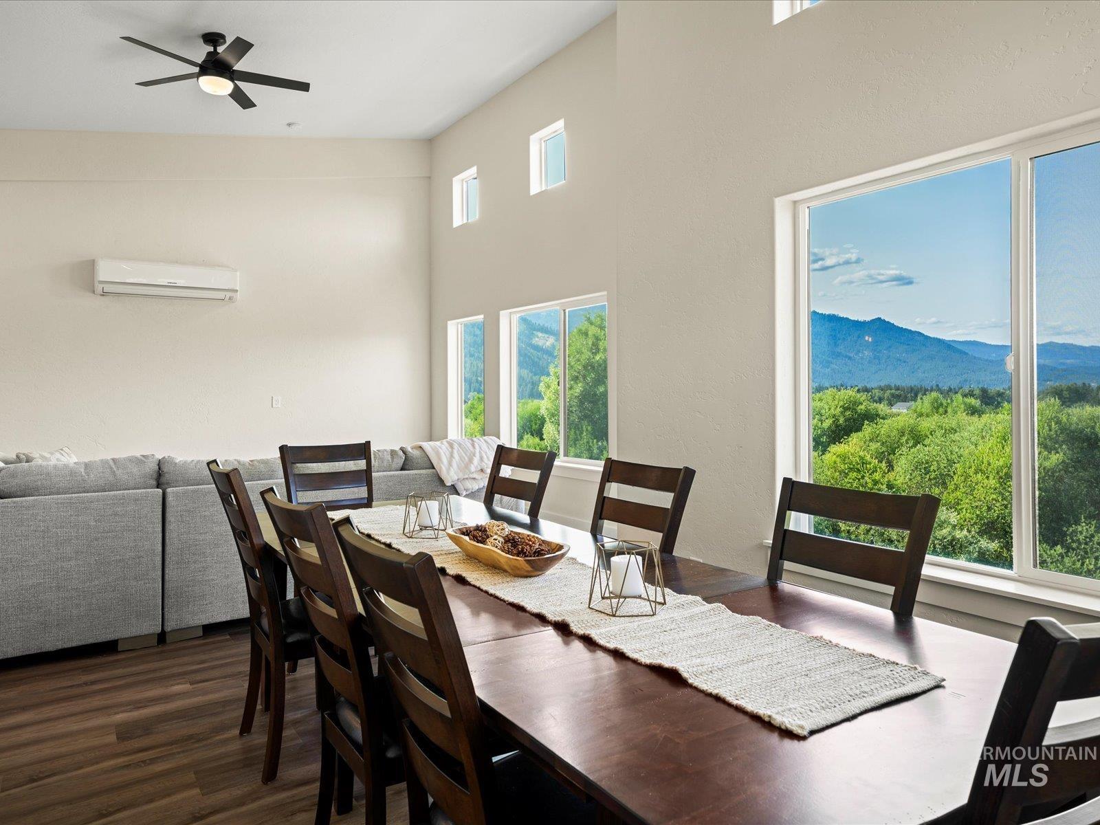 Dining space with an AC wall unit, wood finished floors, a ceiling fan, and a mountain view