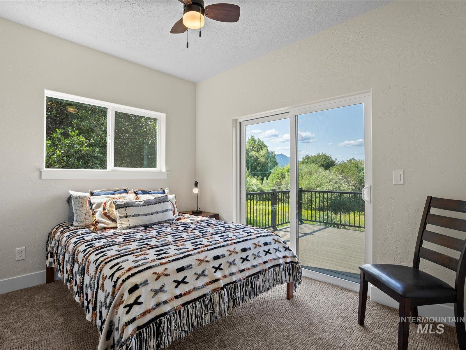 Carpeted bedroom featuring access to exterior, a textured wall, and ceiling fan