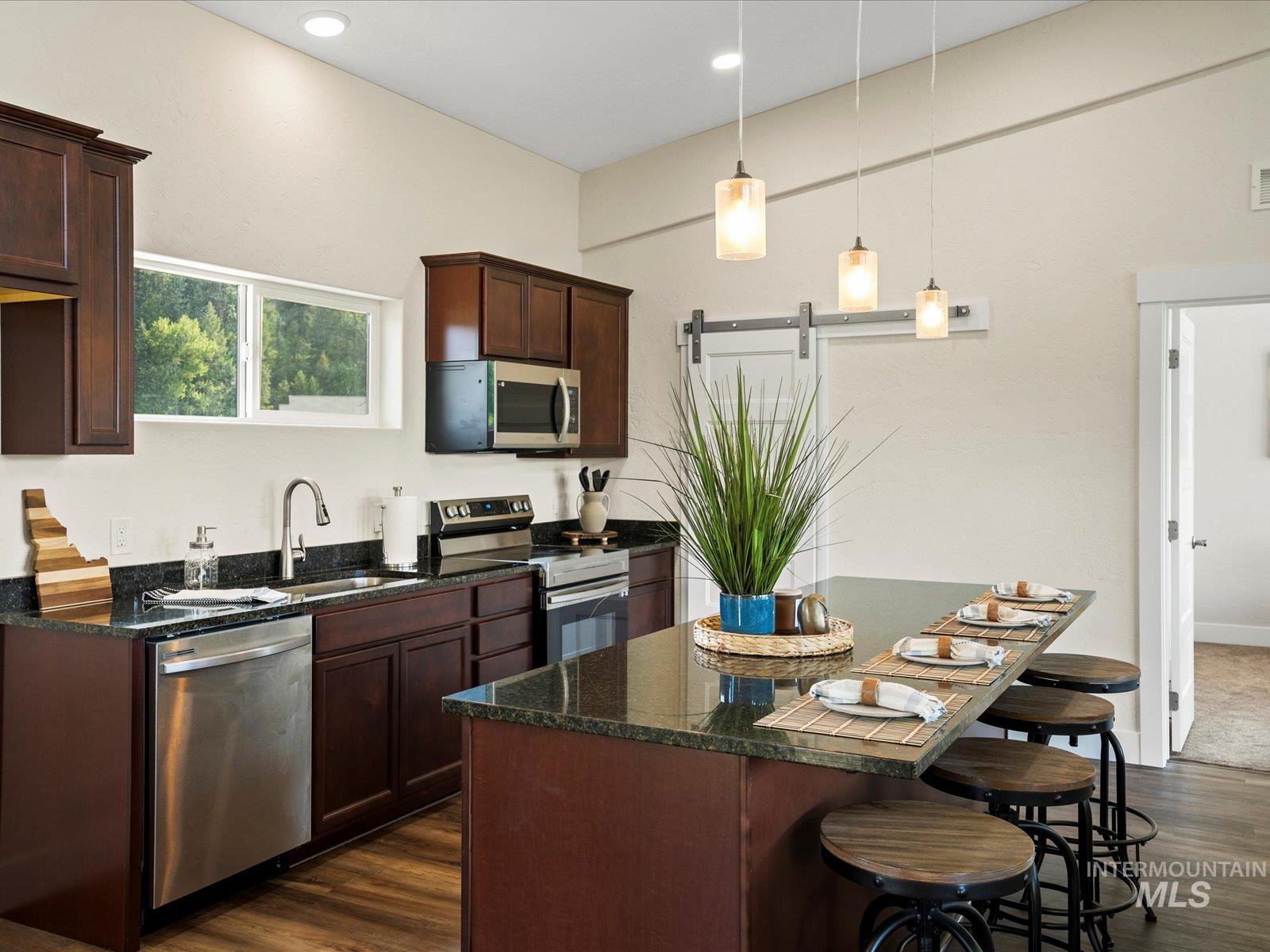 Kitchen featuring appliances with stainless steel finishes, dark wood-style flooring, a breakfast bar, a center island, and recessed lighting