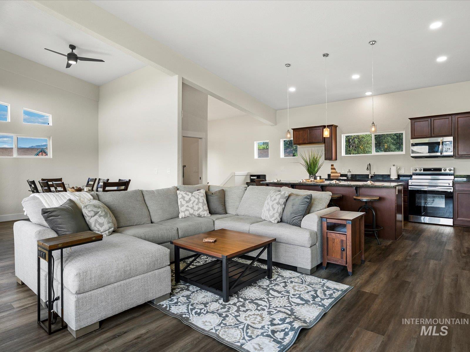 Living area featuring dark wood-type flooring, recessed lighting, a ceiling fan, and beam ceiling