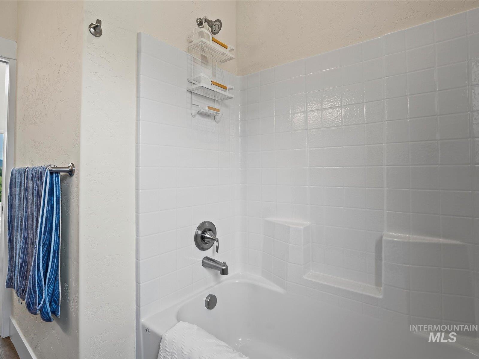 Full bath with  shower combination and a textured wall