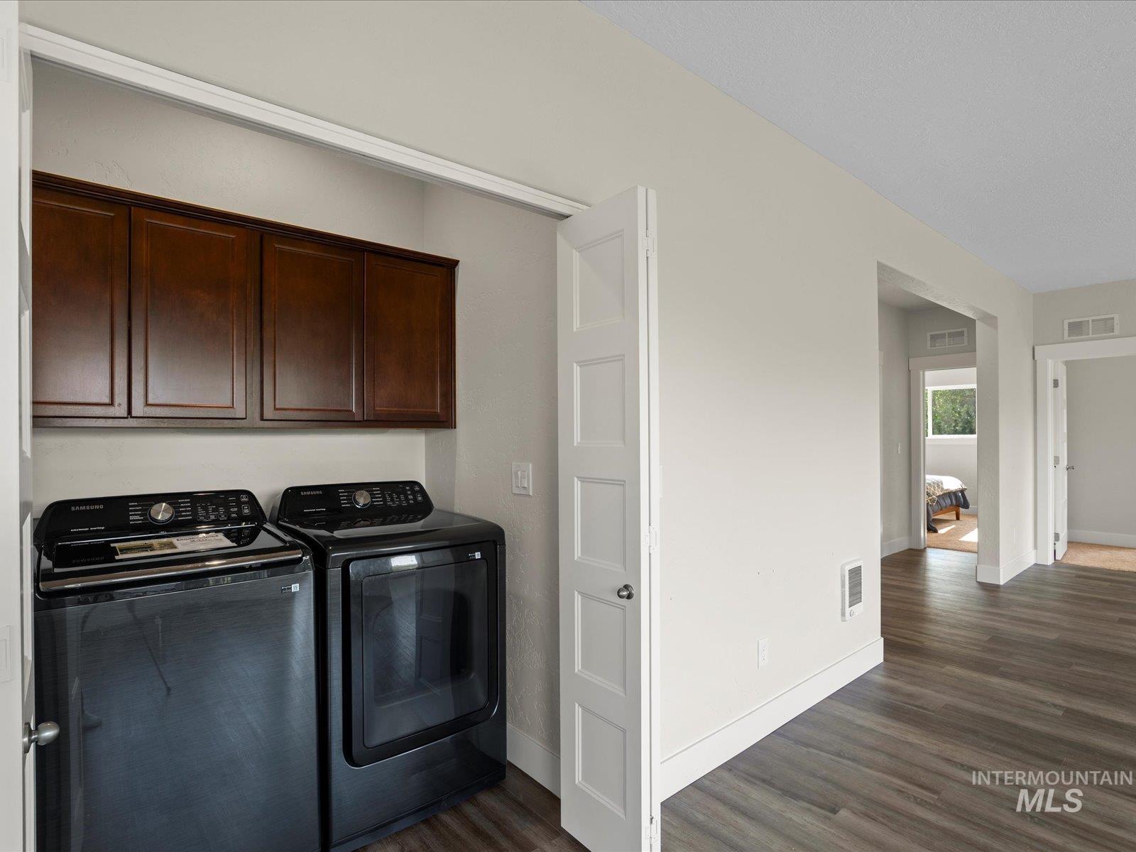 Washroom with cabinet space, separate washer and dryer, and dark wood-style flooring