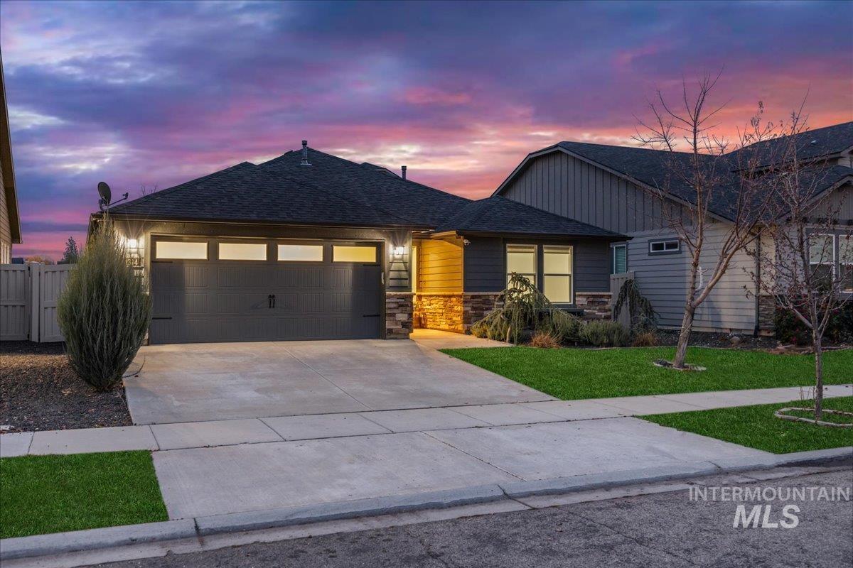 View of front facade featuring stone siding, concrete driveway, a garage, and a shingled roof