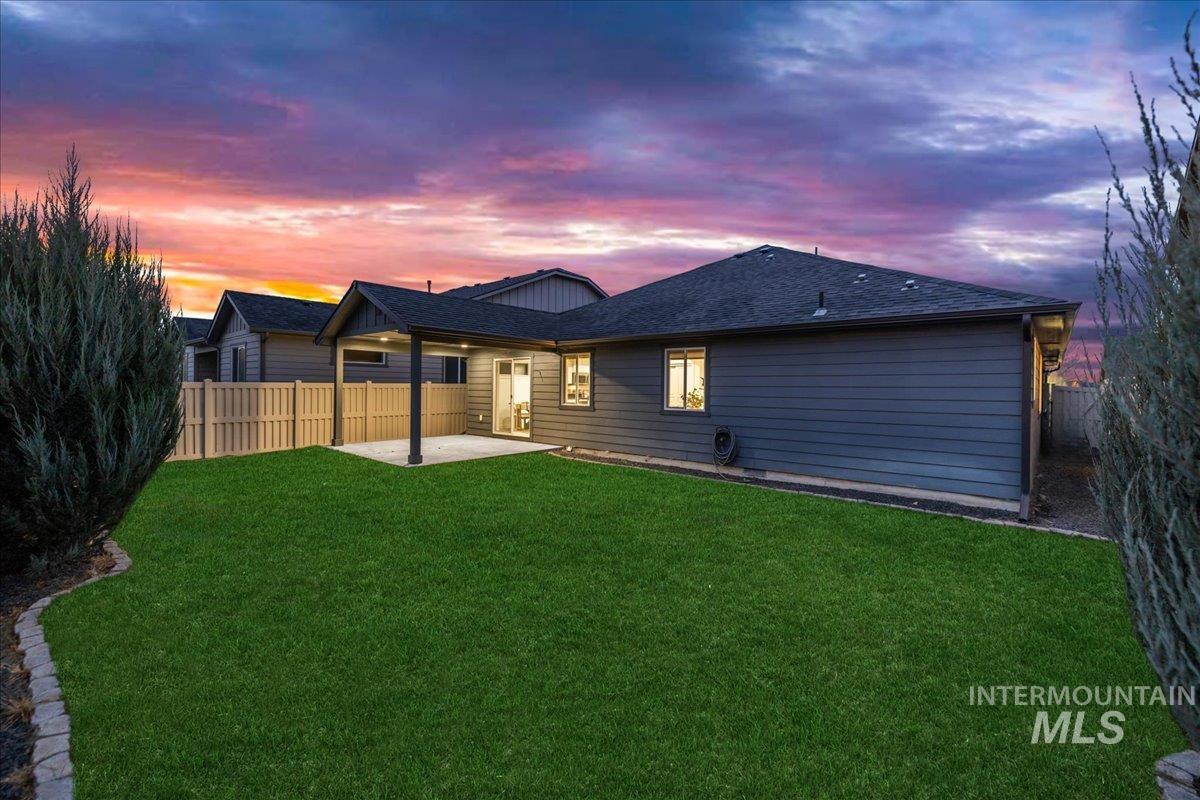 Rear view of house with a patio area, a fenced backyard, and a shingled roof