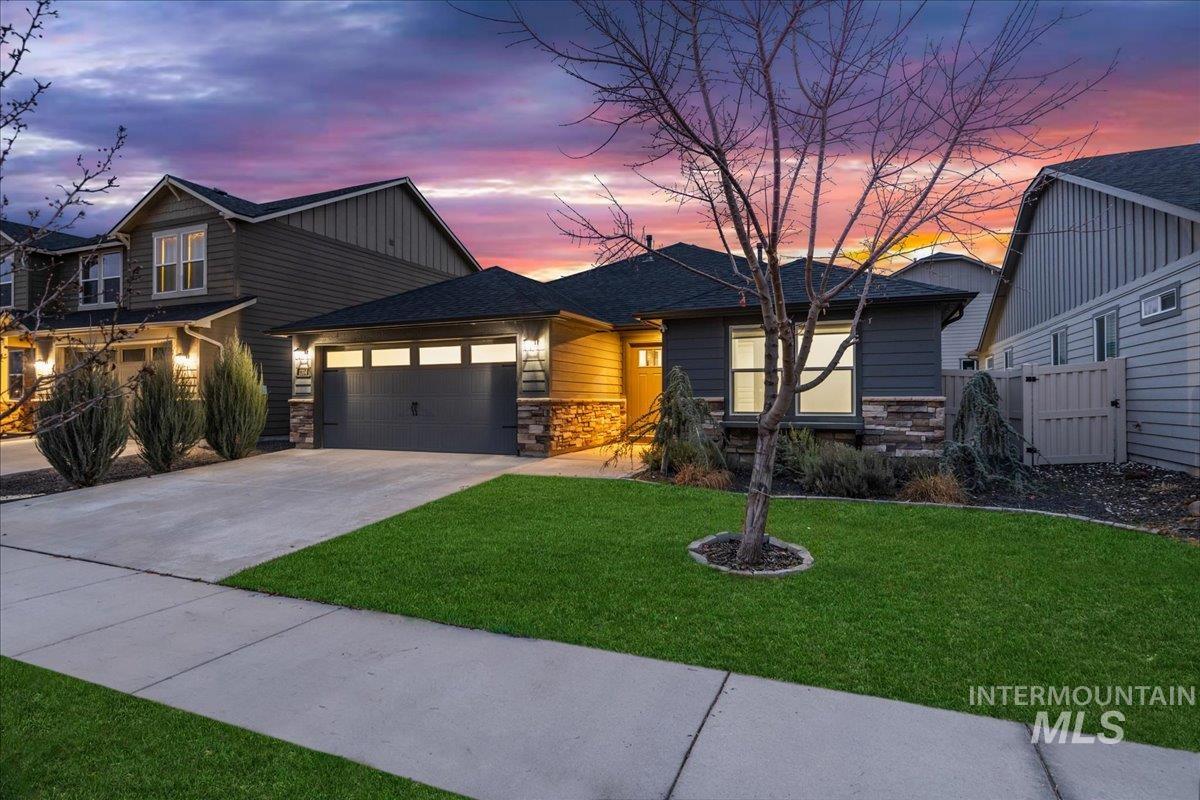 View of front of house with stone siding, driveway, and an attached garage