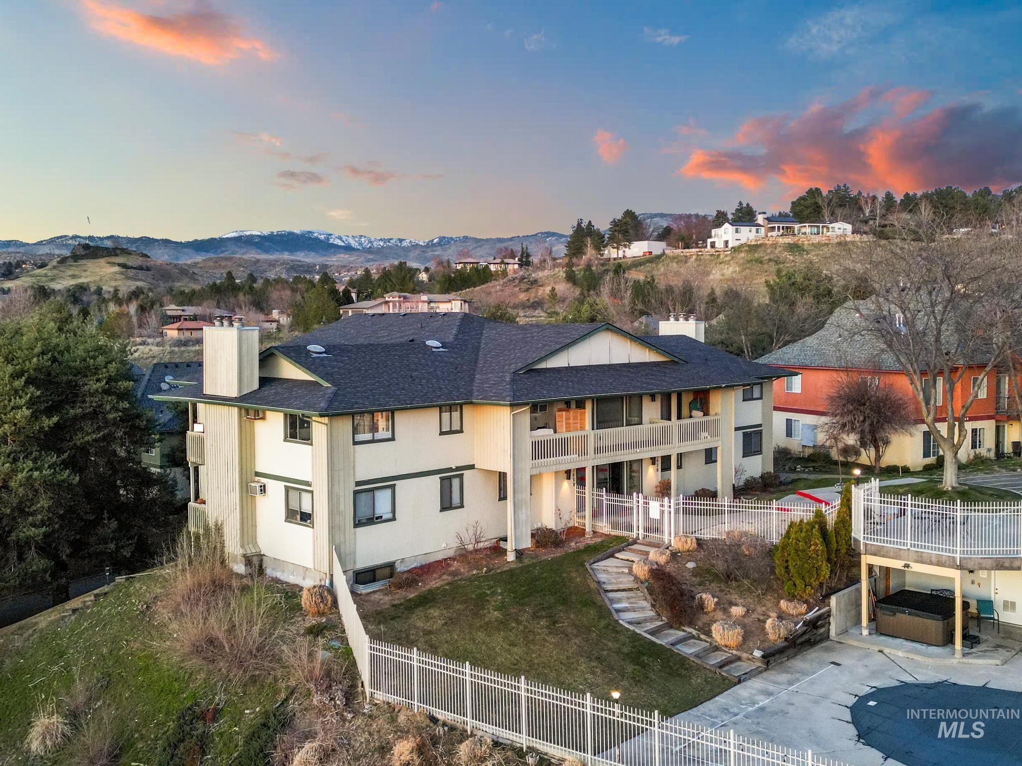 Back of property at dusk featuring a chimney, a mountain view, a balcony, and roof with shingles