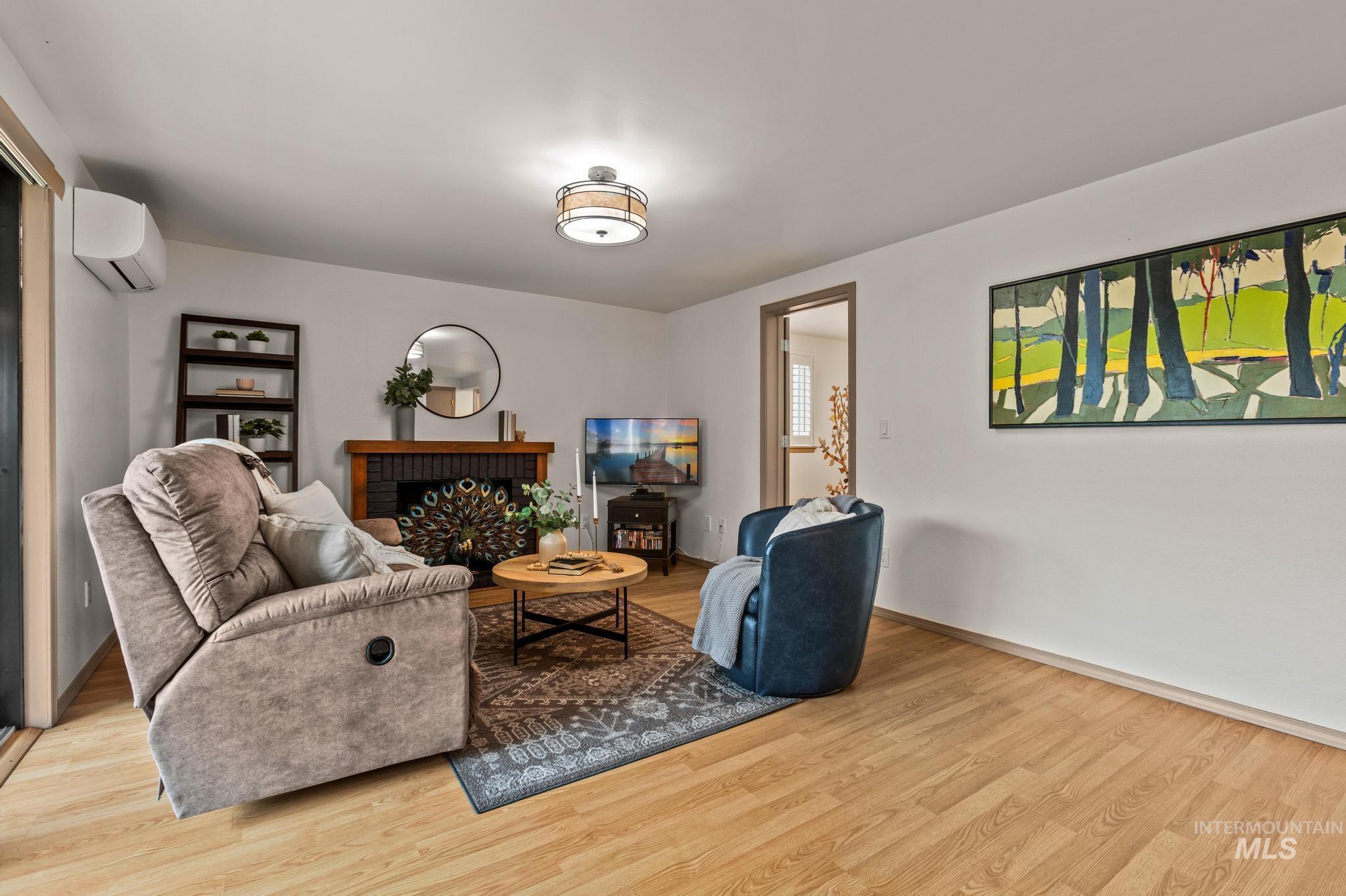 Living area with wood finished floors, a fireplace, and a mini split for heating / cooling