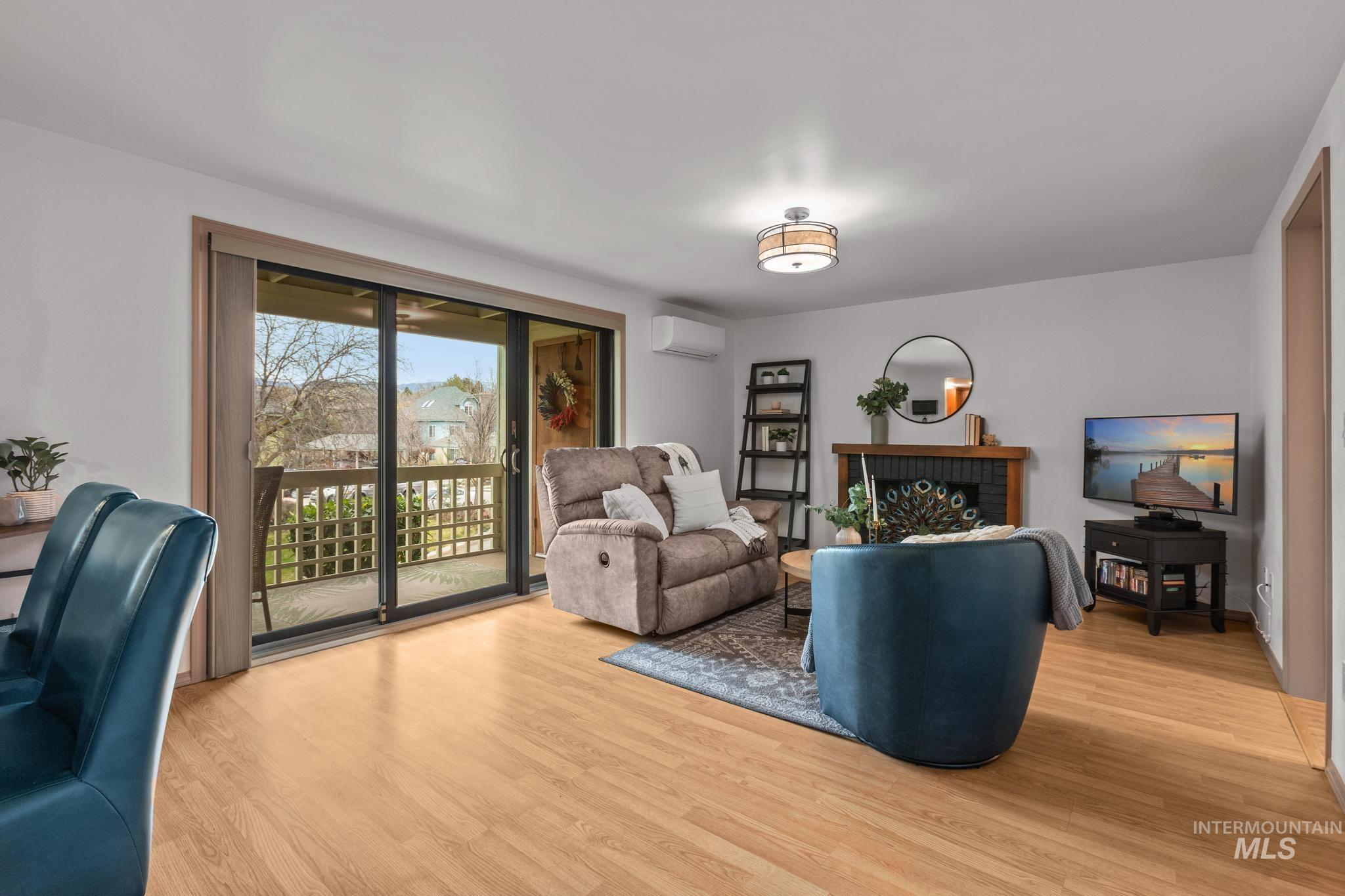 Living area featuring wood finished floors, a brick fireplace, and a mini split for heating / cooling