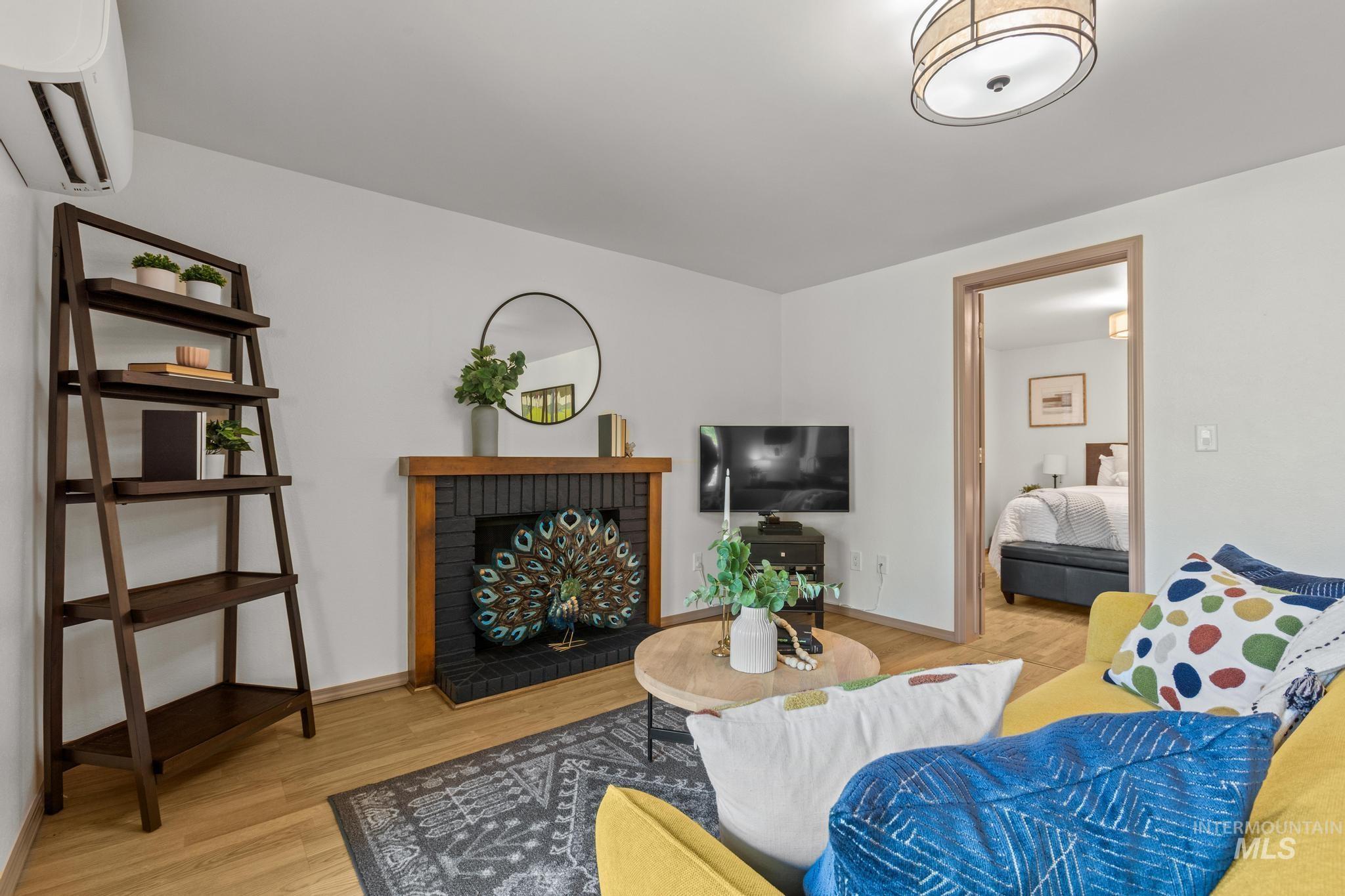 Living room featuring a wall mounted mini split, a fireplace, and light wood-style floors