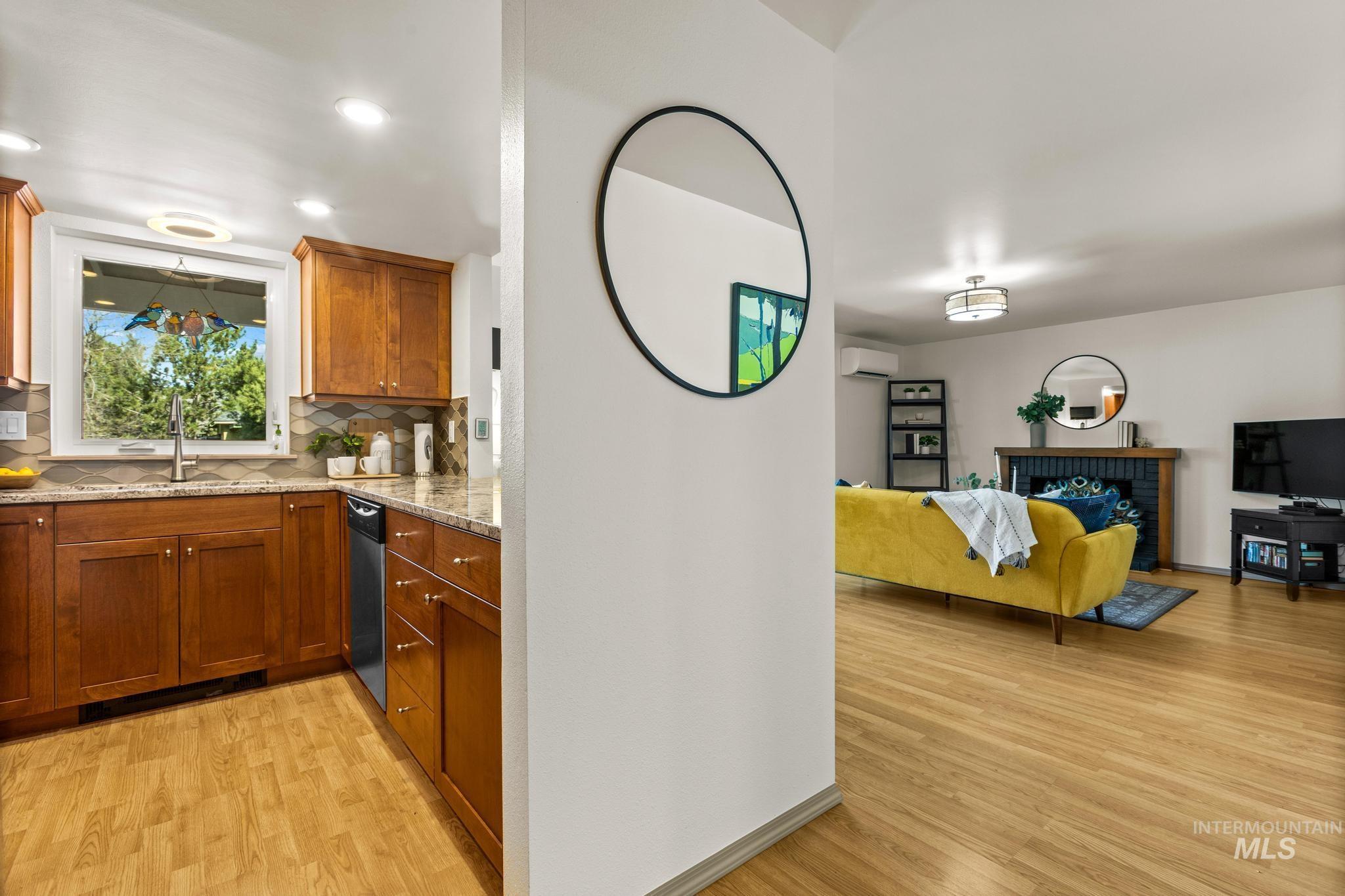Kitchen featuring wood finish cabinetry, light wood finished floors, decorative backsplash, a fireplace, and light stone counters