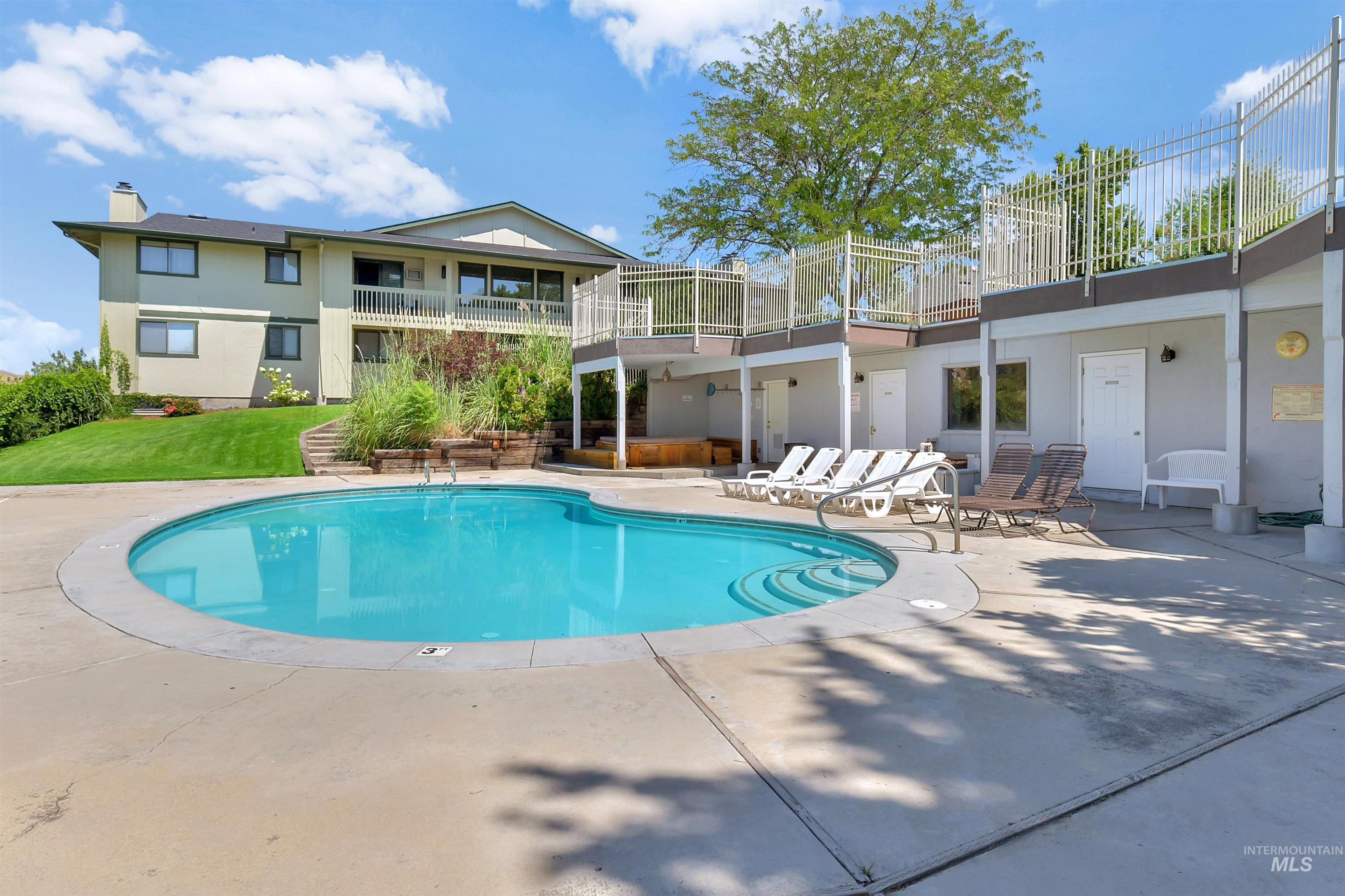 Community pool with a patio, a balcony, and a lawn