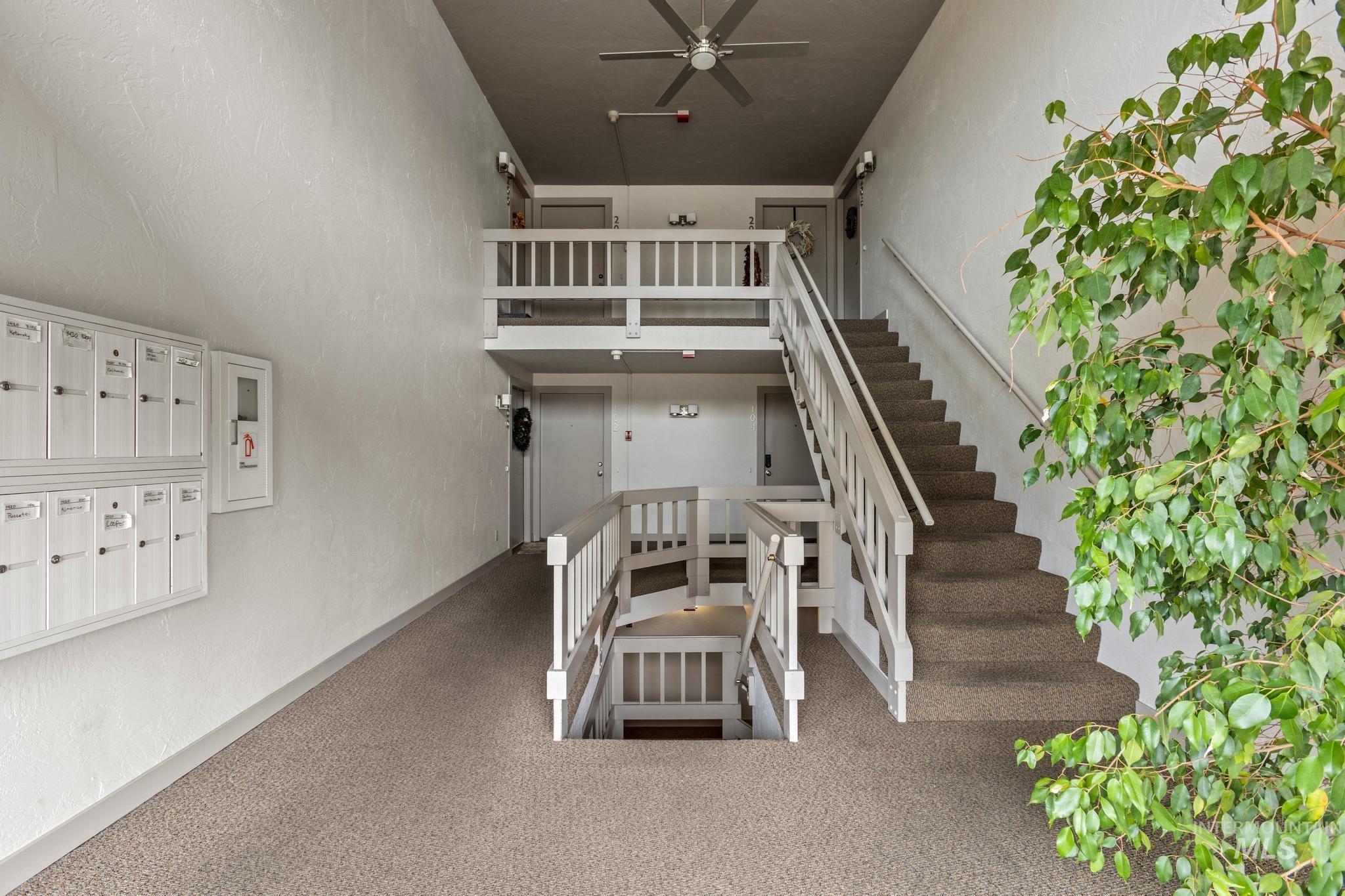 Stairs with a textured wall, a ceiling fan, and mail area