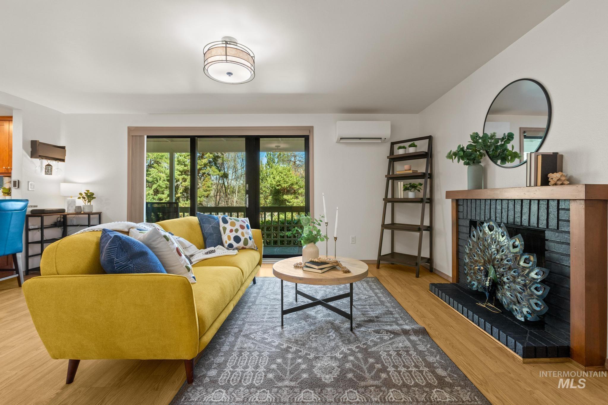 Living area with a fireplace, wood finished floors, and a wall mounted mini split