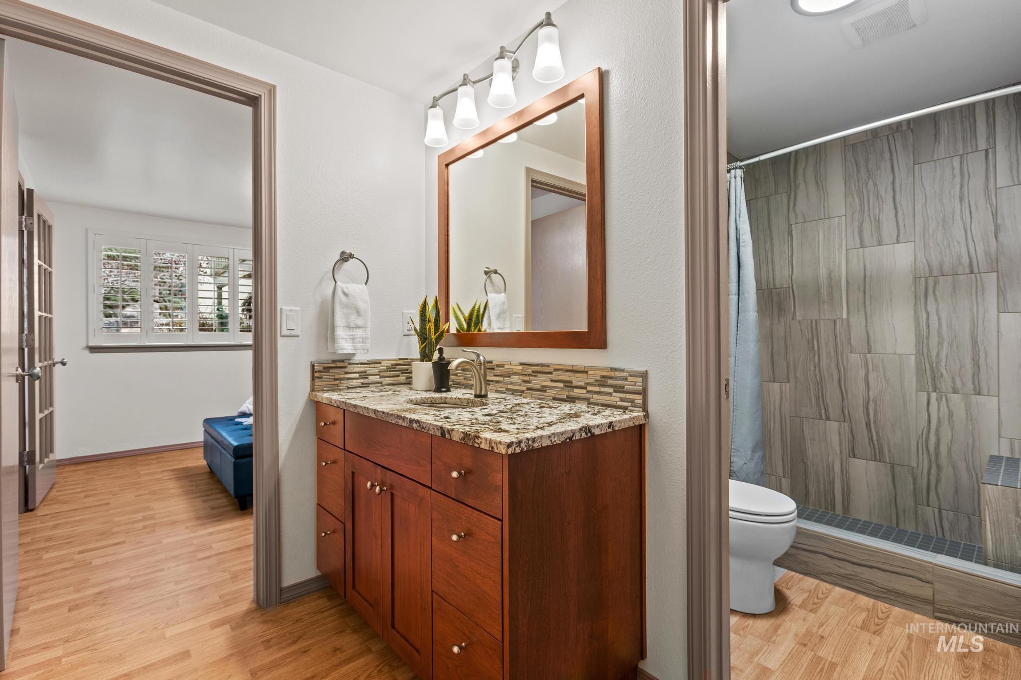Bathroom featuring vanity, light wood-style flooring, and a shower stall