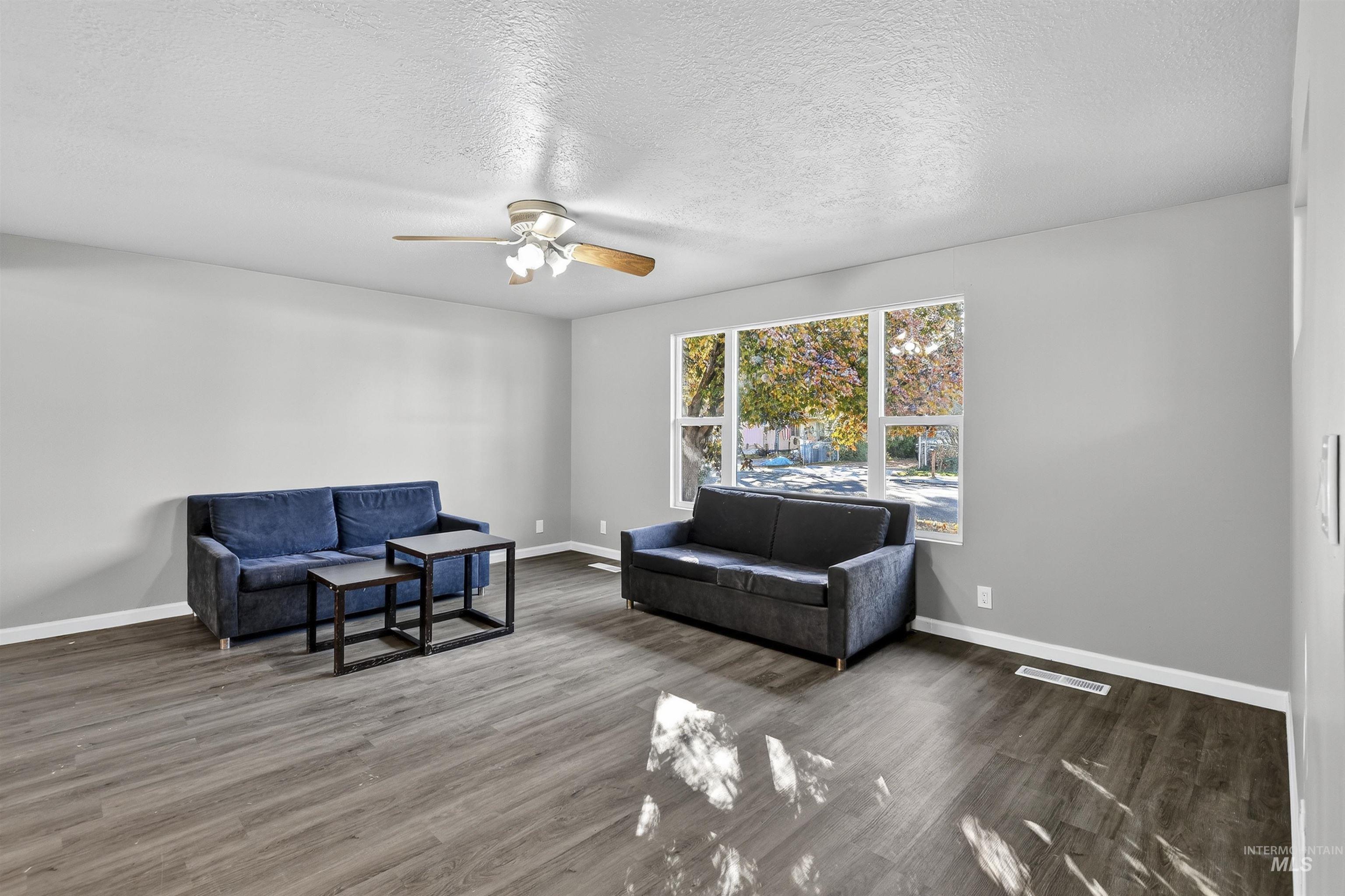 Sitting room with a ceiling fan, wood finished floors, and a textured ceiling