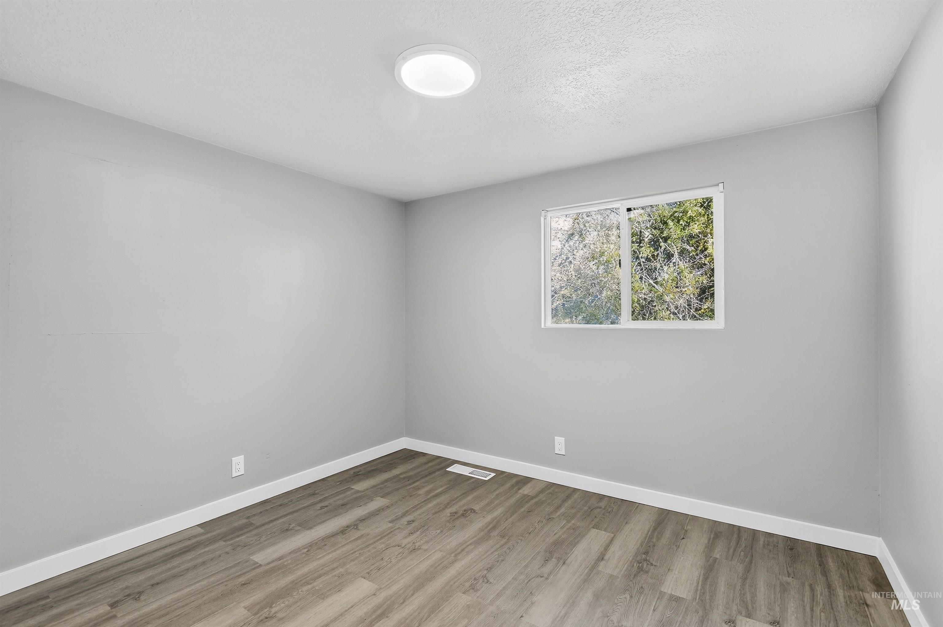 Unfurnished room with light wood-style flooring and a textured ceiling