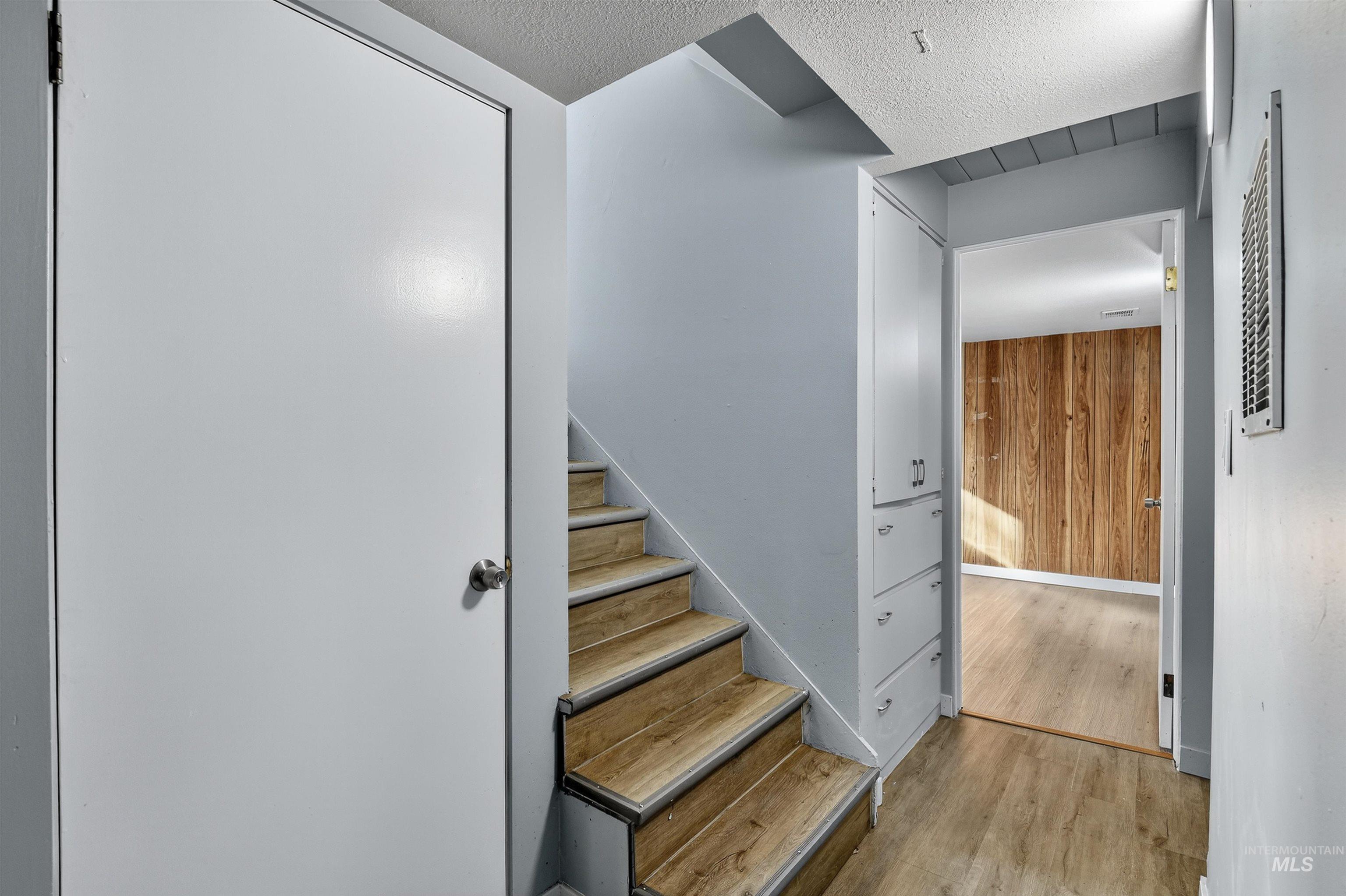 Stairway featuring wood finished floors, wooden walls, and a textured ceiling